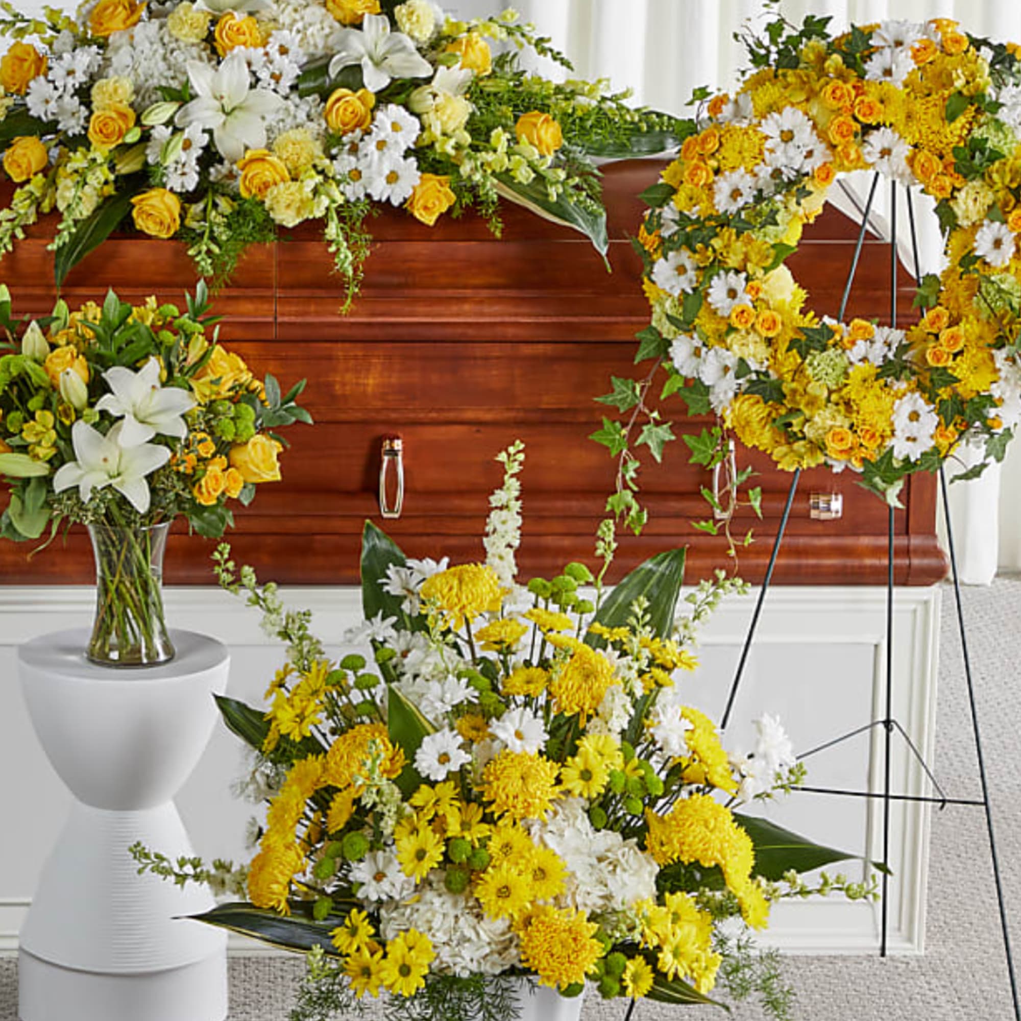 Yellow and white floral funeral arrangements around a polished wooden casket
