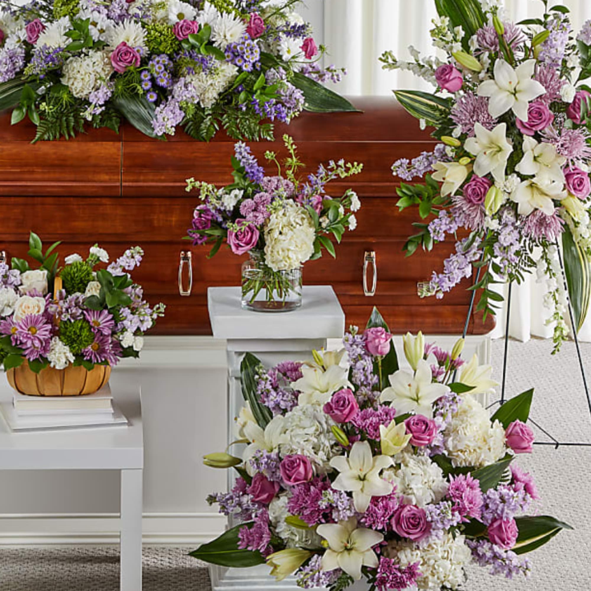 Floral funeral arrangements with white lilies, pink roses, and purple flowers