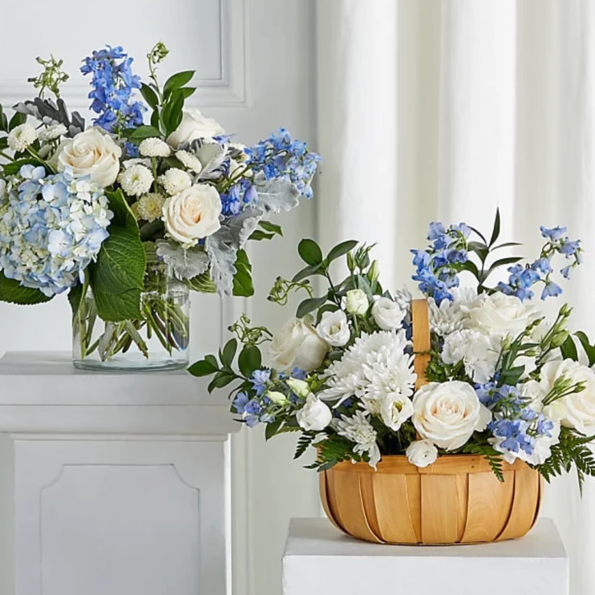 Two blue and white floral arrangements, one in a glass vase and one in a wooden basket