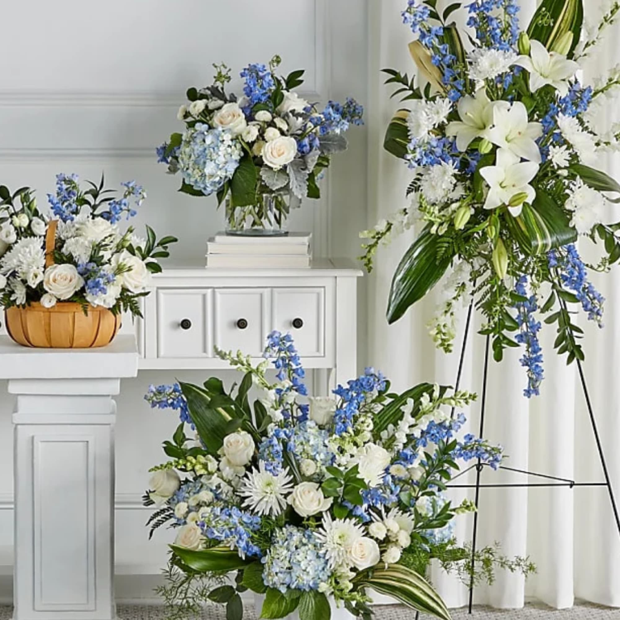 Blue and white floral arrangements in glass and basket containers