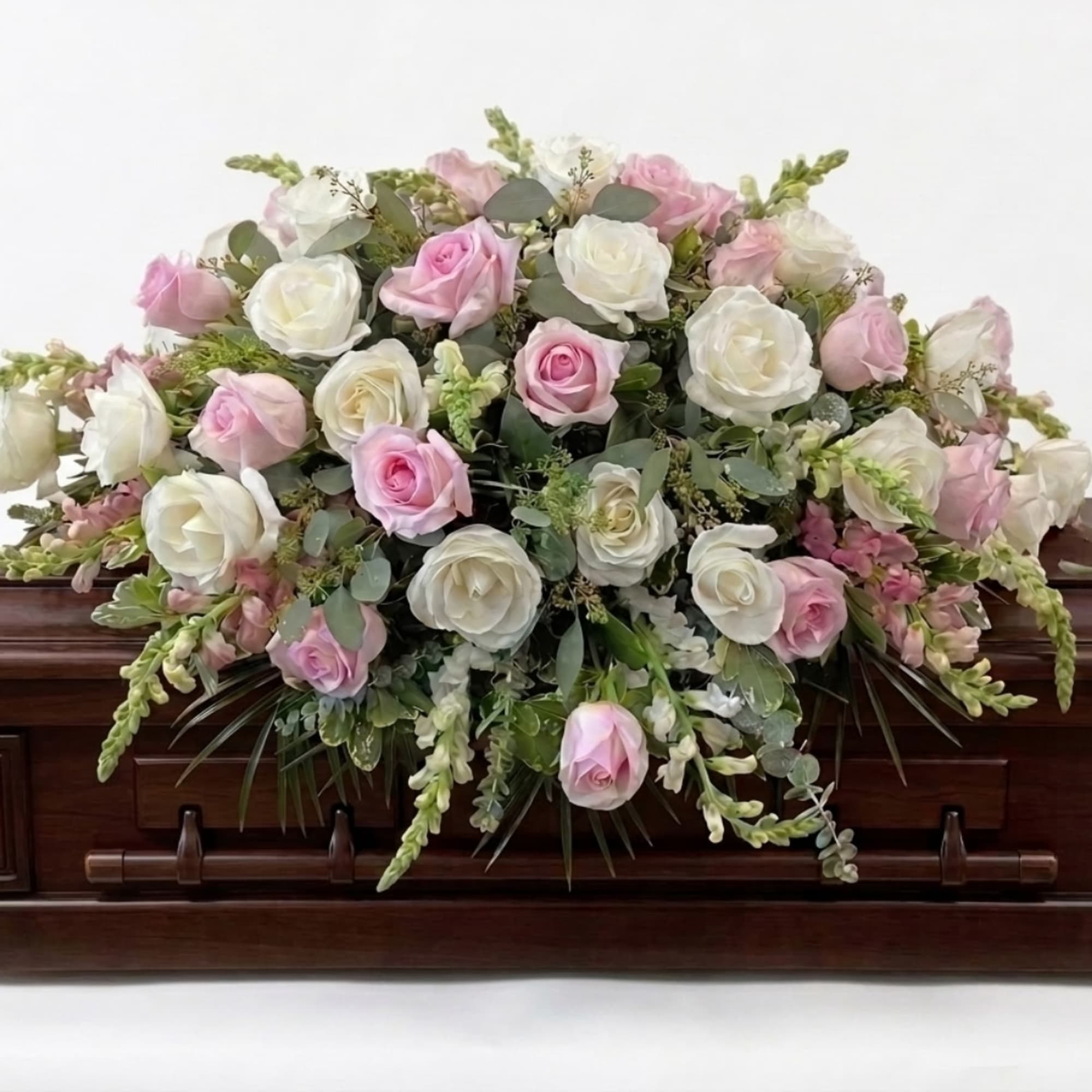 Pink and white rose arrangement on a dark wooden casket