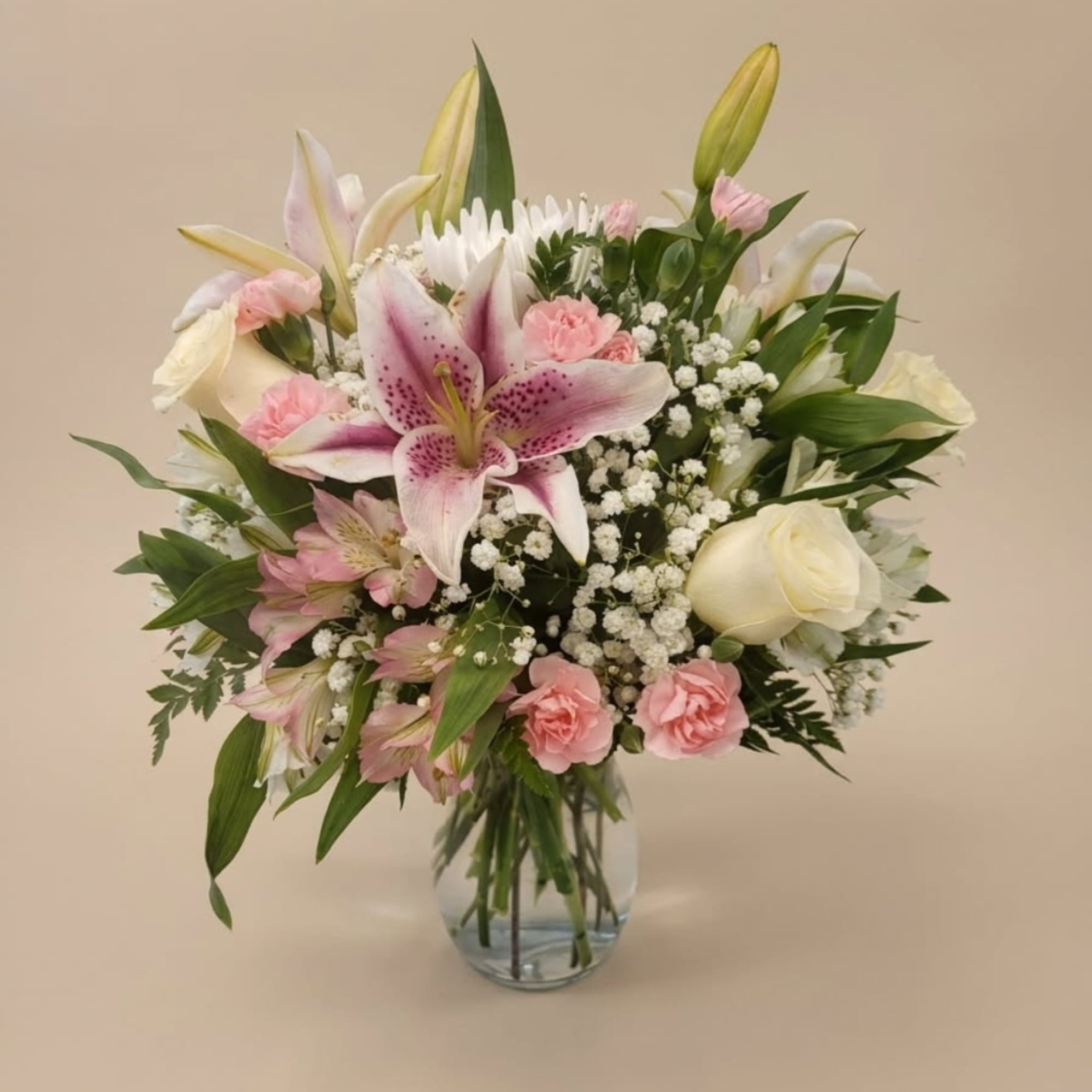 Pink lilies and roses arranged in a clear glass vase