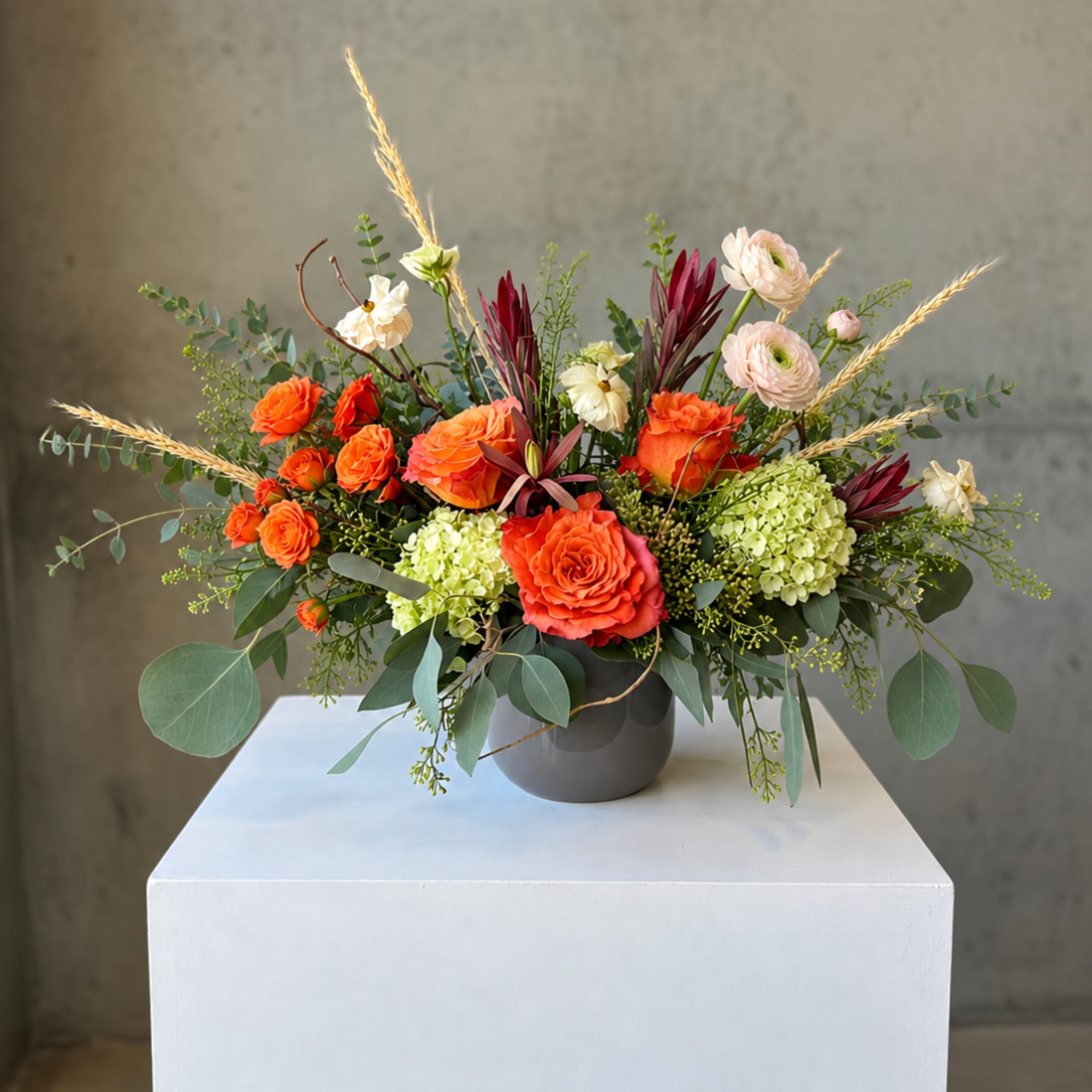 Orange and pale pink floral arrangement in a gray vase