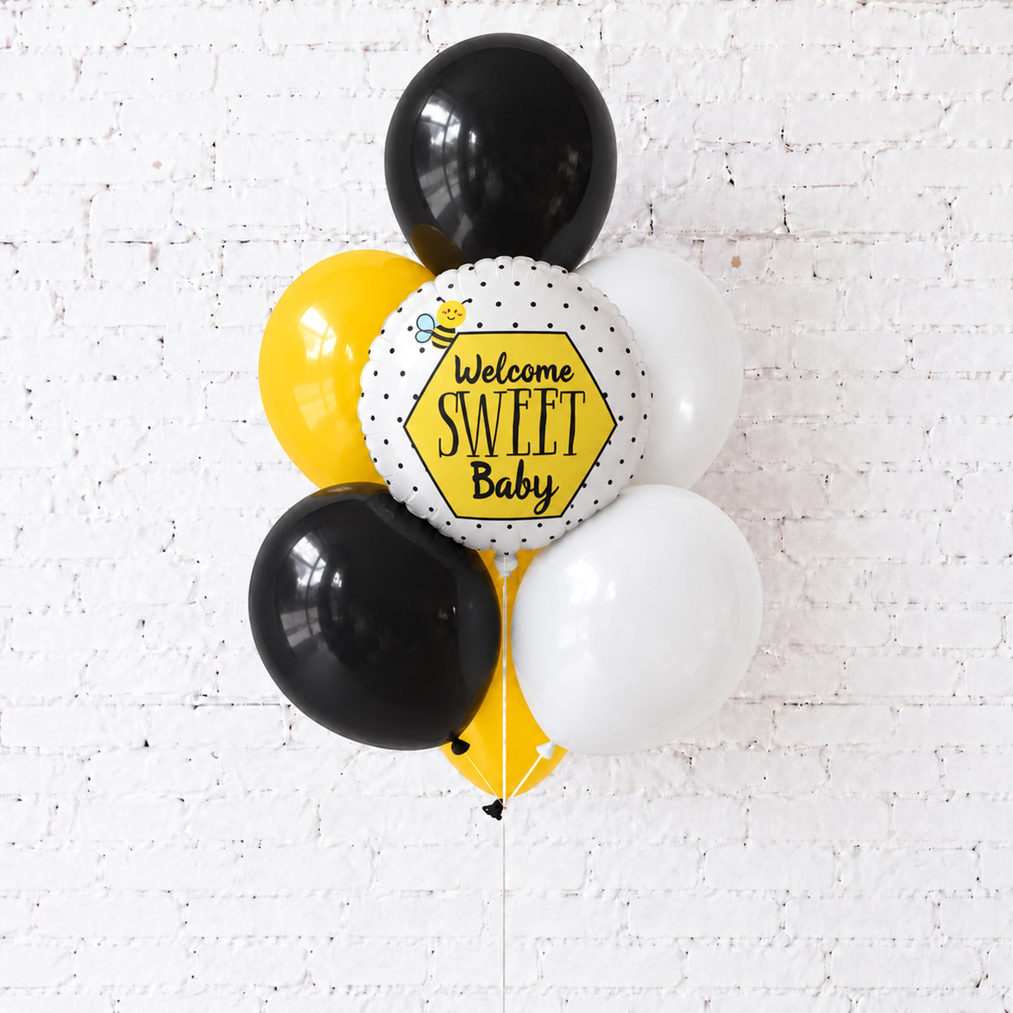 Black, white, and yellow balloons with a "Welcome Sweet Baby" balloon centerpiece