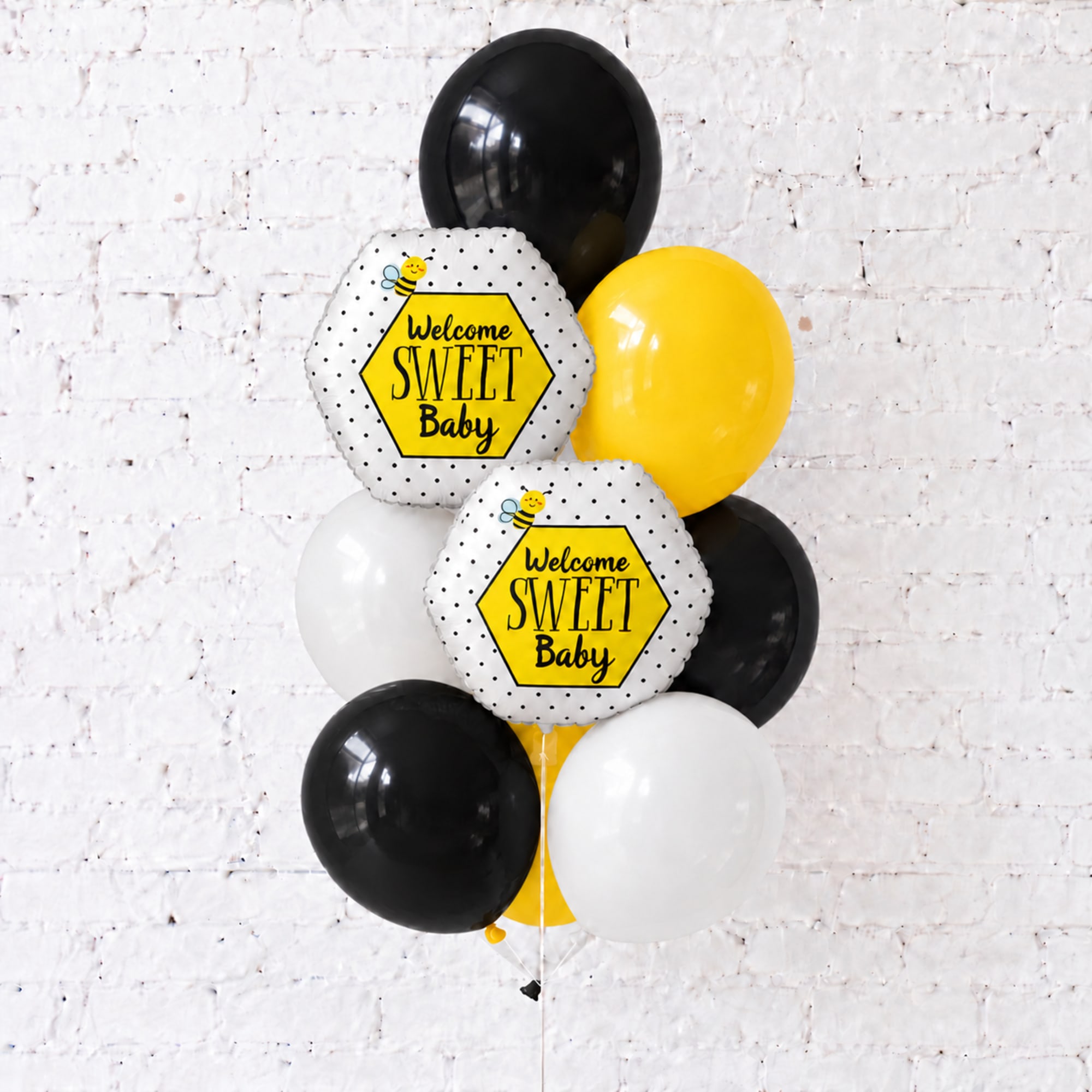 Black, white, and yellow baby shower balloons with "Welcome Sweet Baby" signs