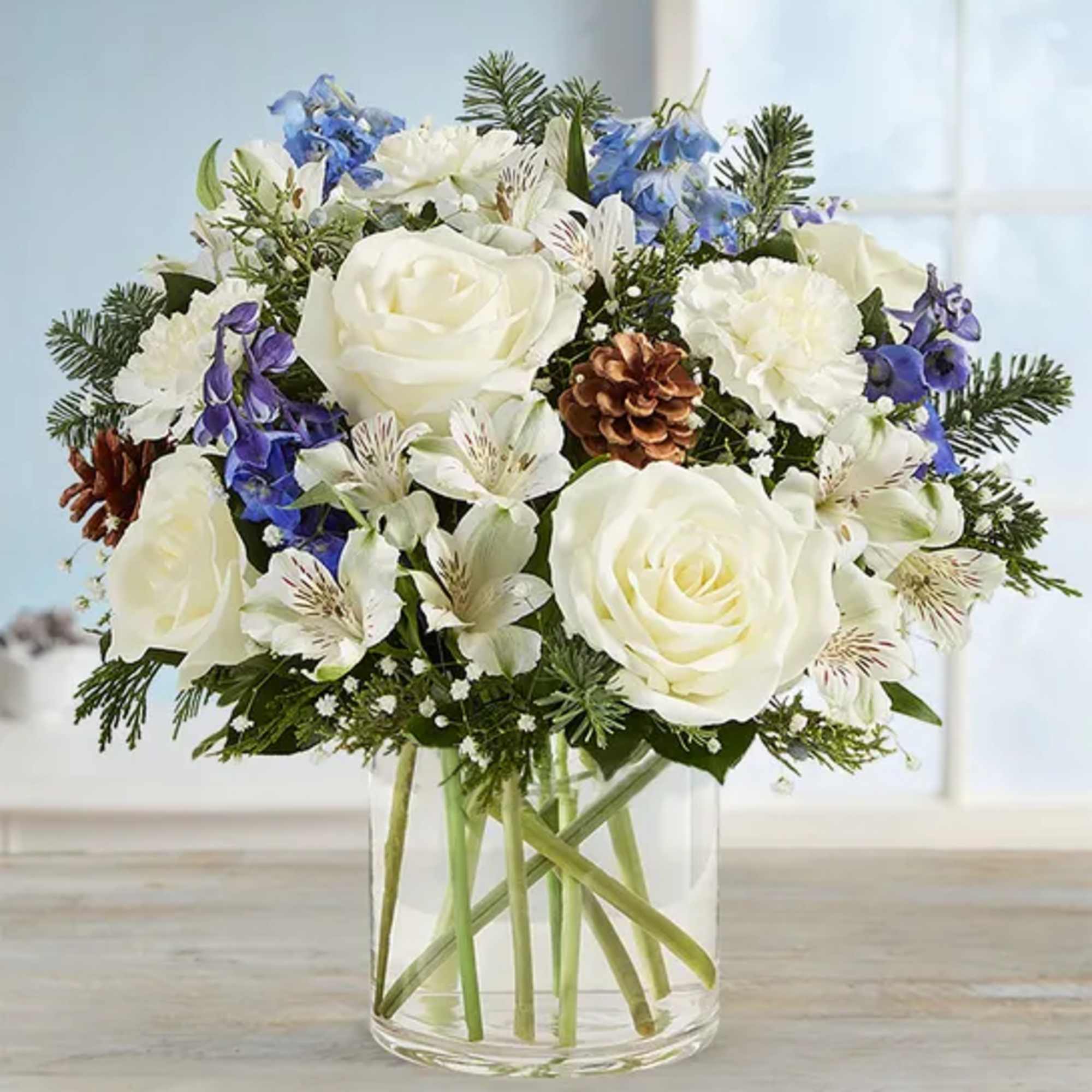 White roses and blue flowers in a clear glass vase