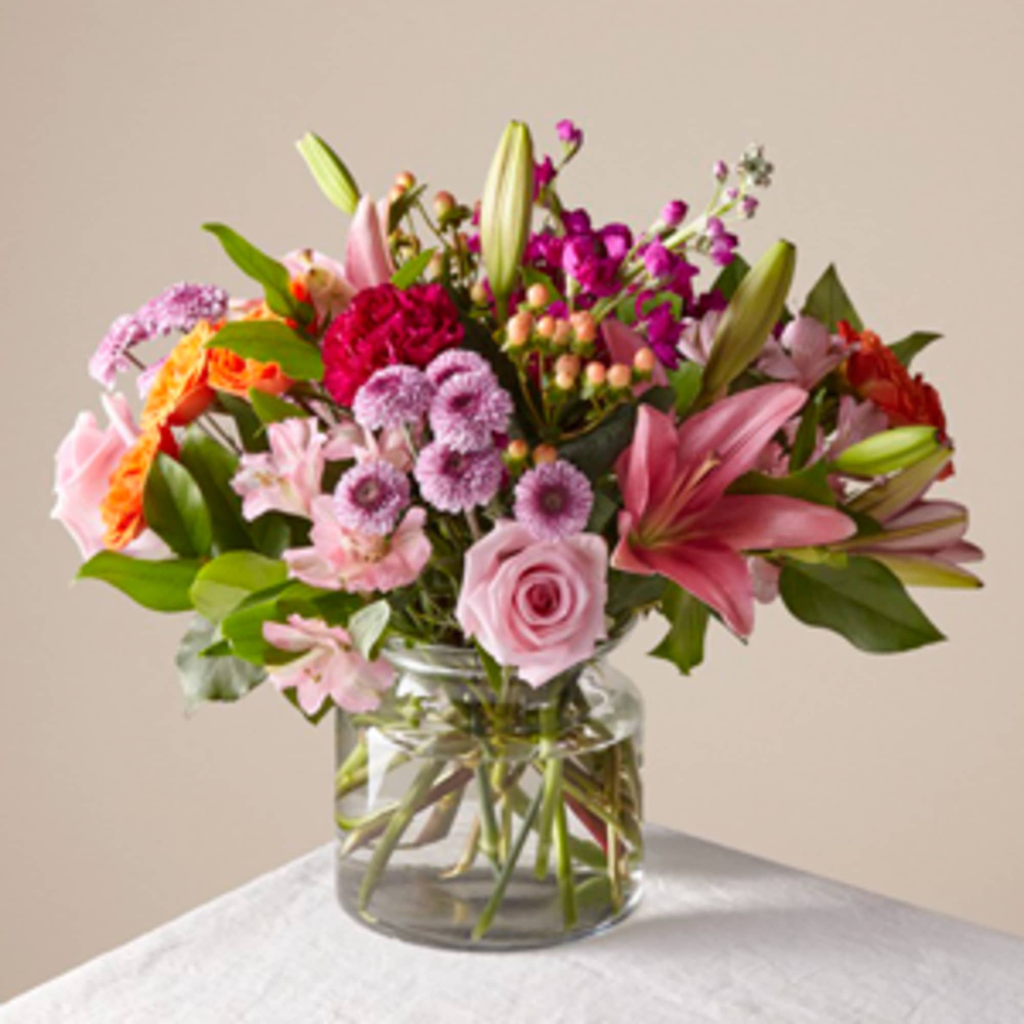 Mixed pink and purple flowers arranged in a clear glass vase