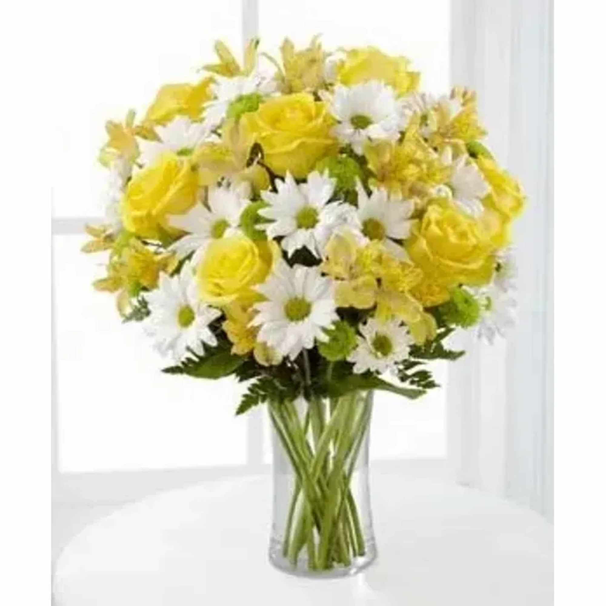 Yellow roses and white daisies arranged in a clear glass vase