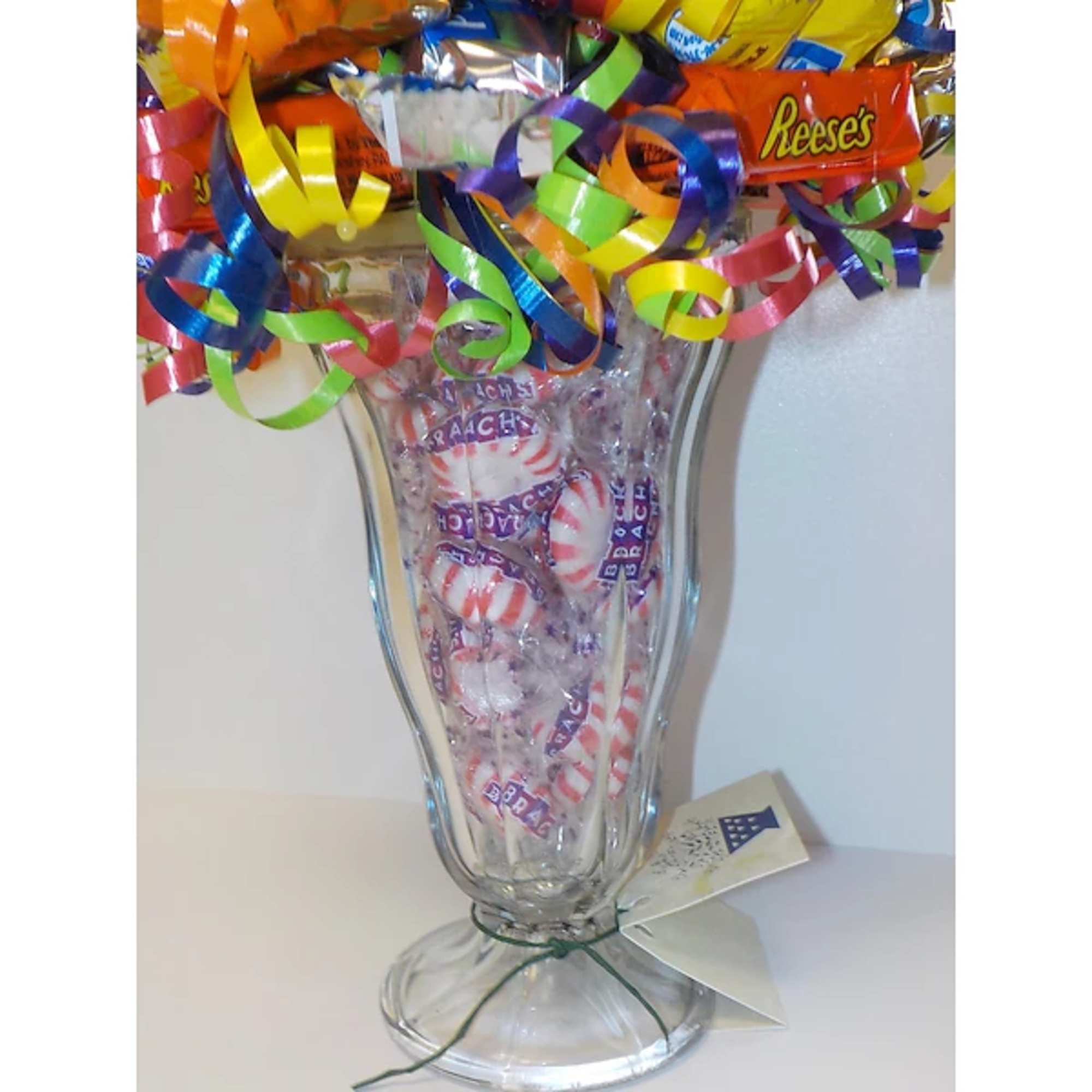 Clear glass vase filled with wrapped candy and colorful curling ribbons
