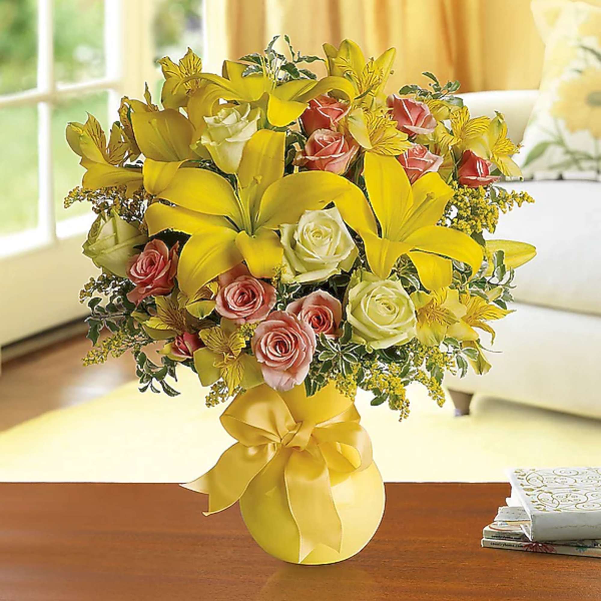 Yellow lilies and pink roses in a vase with a yellow ribbon