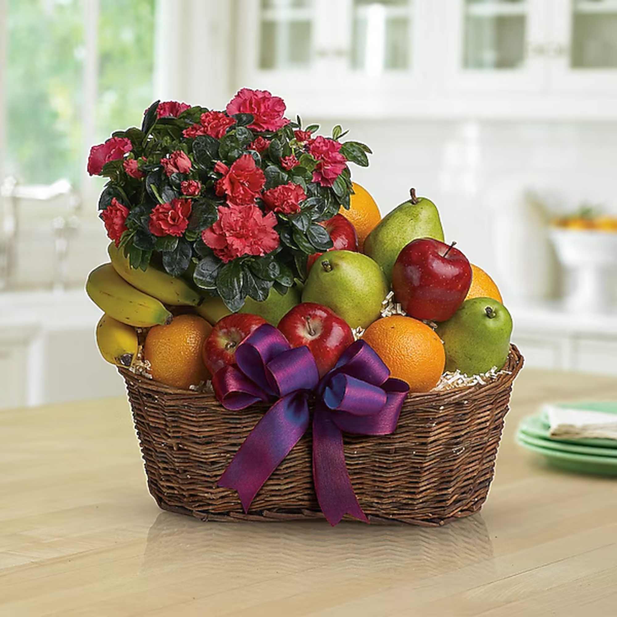 Fruit basket with a potted pink carnation plant and purple ribbon