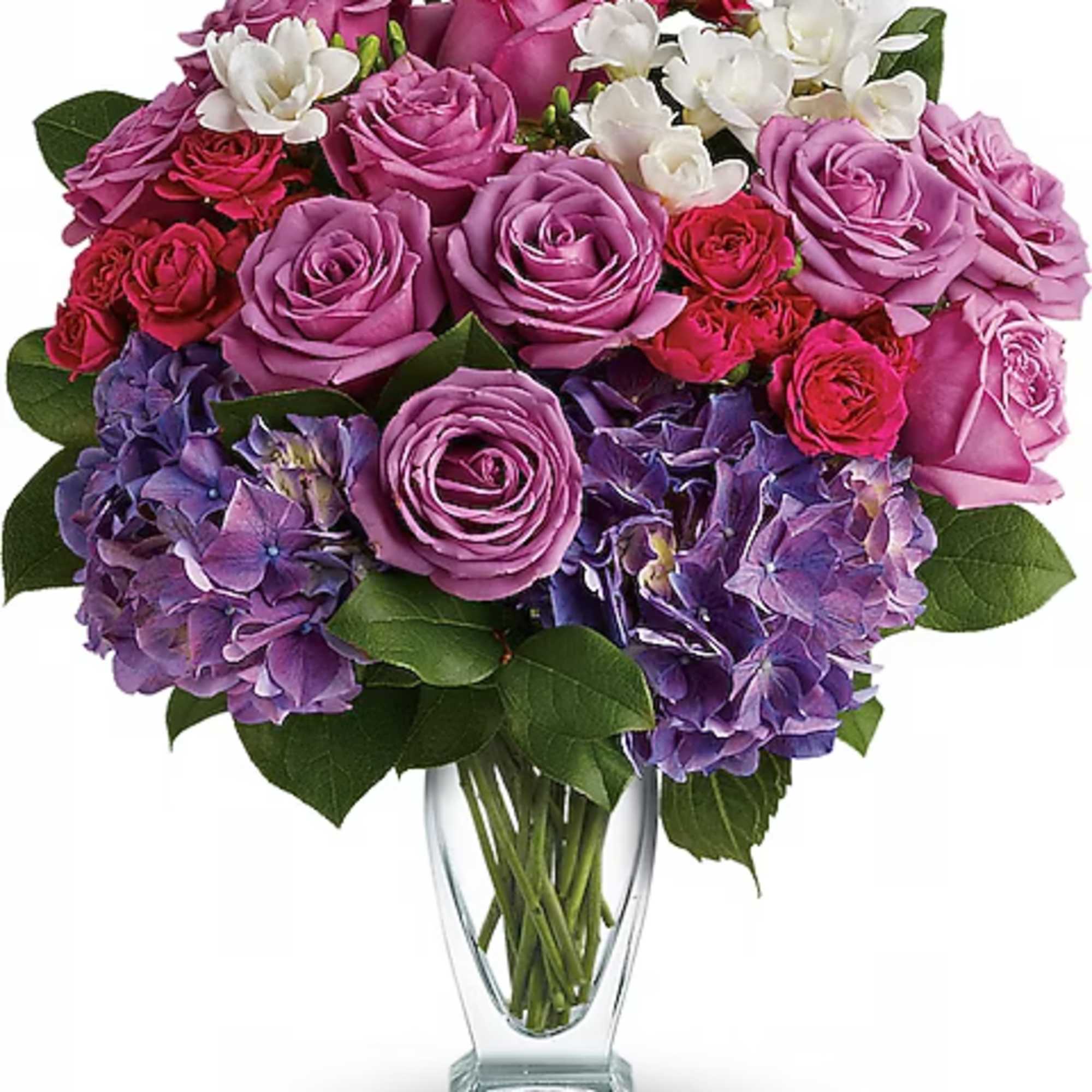 Bouquet of pink and purple roses with white flowers in a clear glass vase