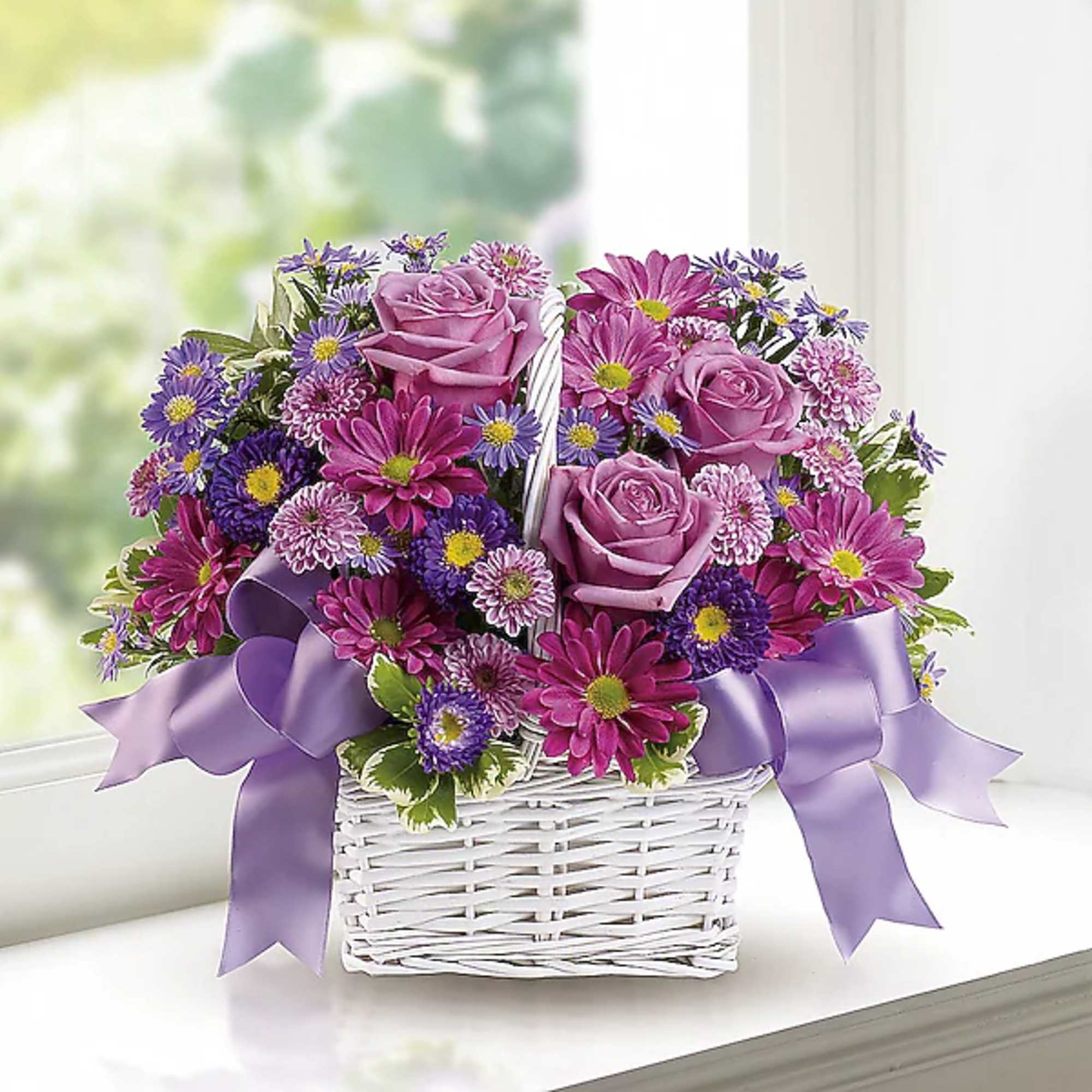 Purple roses and daisy flowers in a white wicker basket with a lavender ribbon
