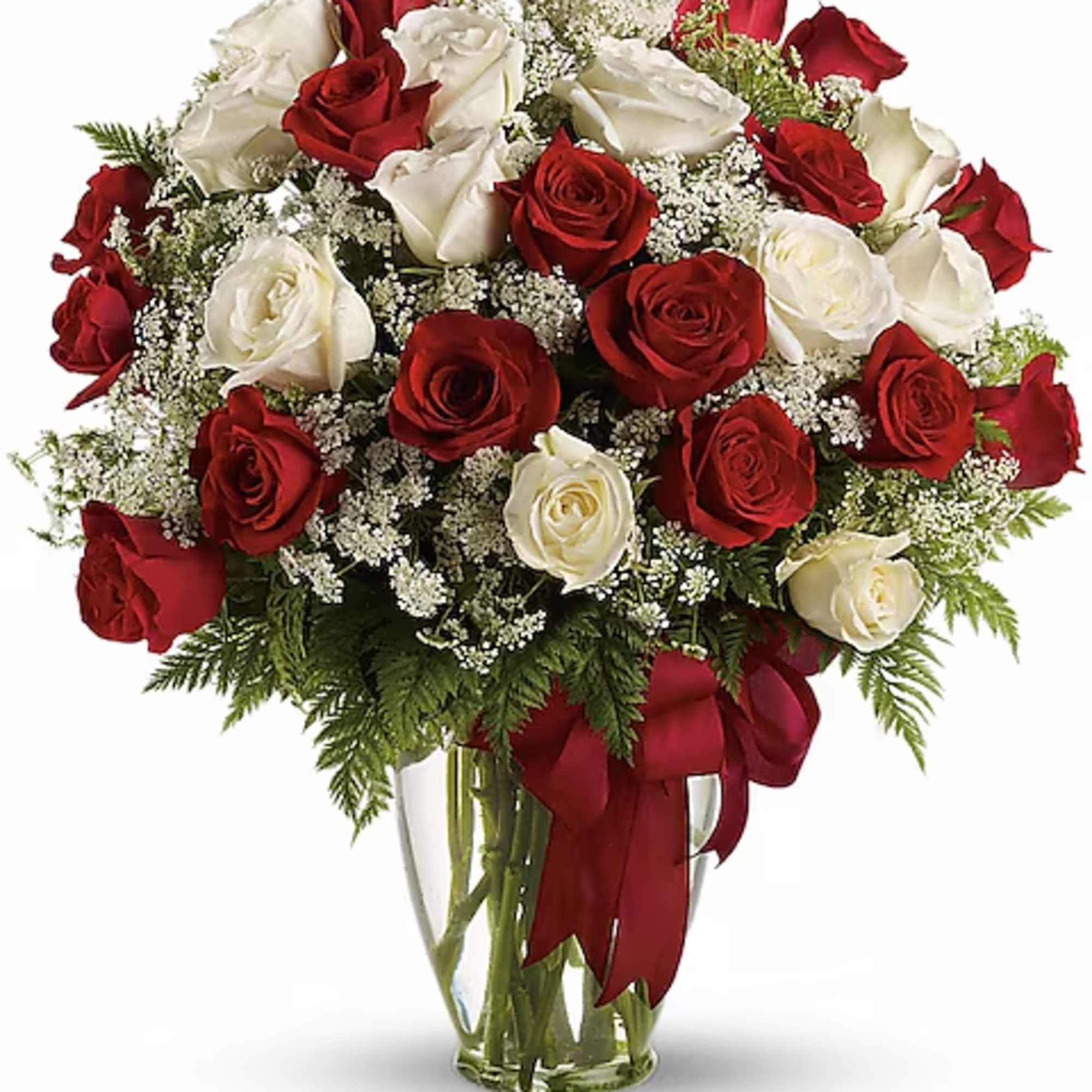 Red and white roses arranged in a clear glass vase with a red ribbon.