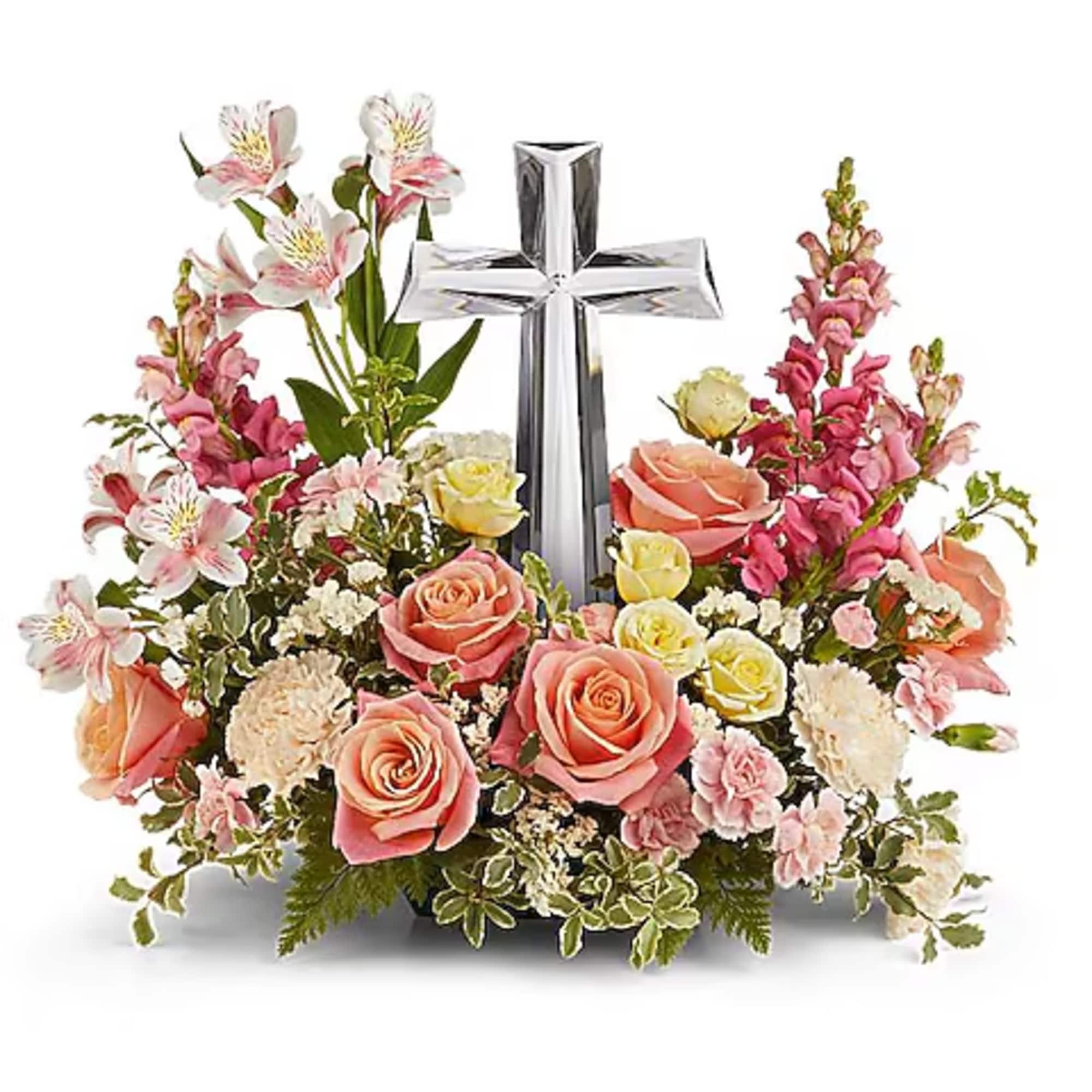 Pink and peach floral arrangement with a silver cross centerpiece