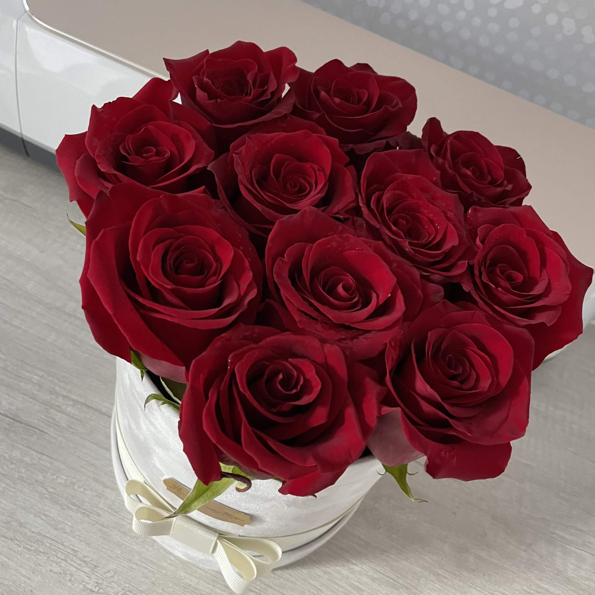 Deep red roses packed in a white round hatbox with a delicate