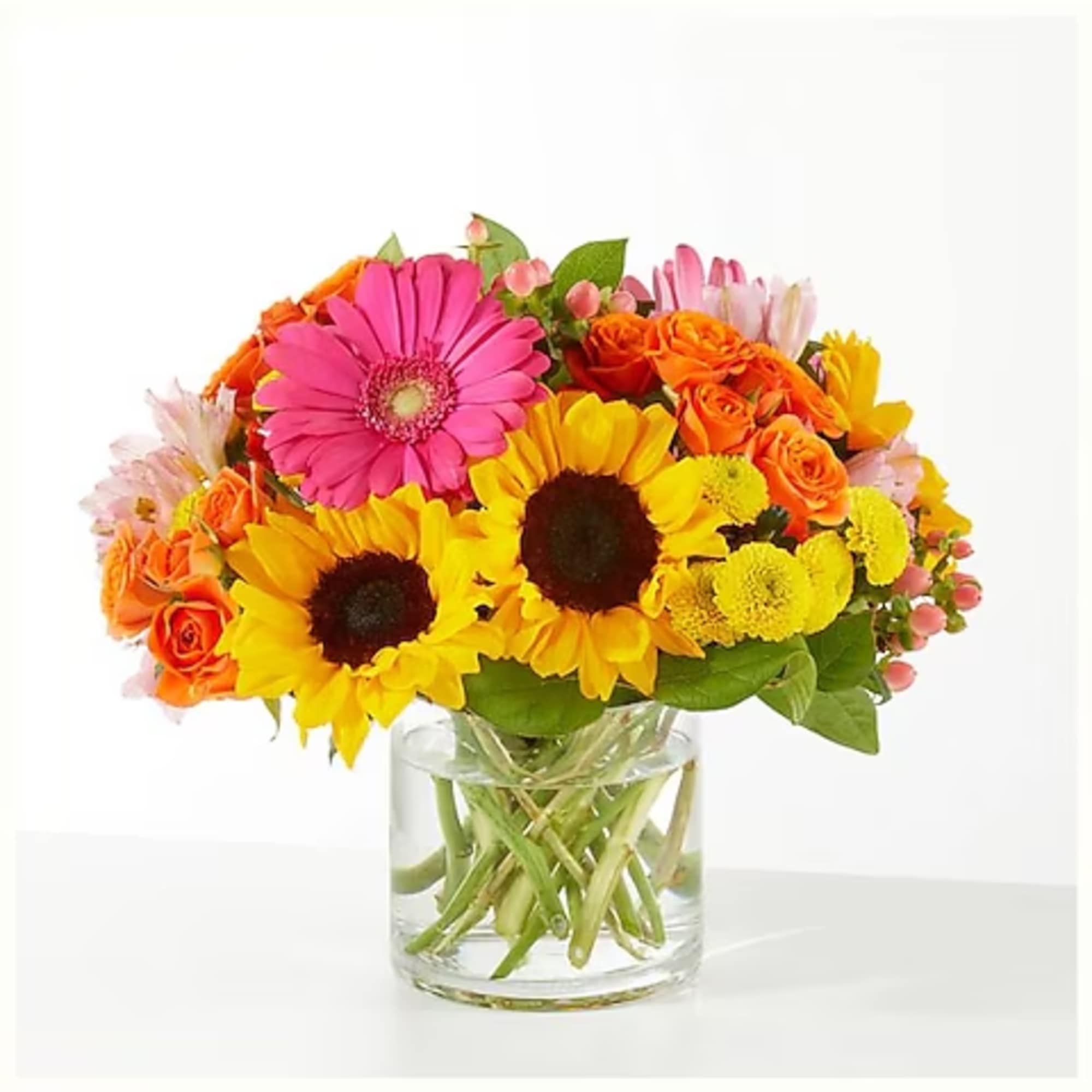 Bright mixed bouquet with sunflowers, gerbera daisies, and orange roses in a glass vase