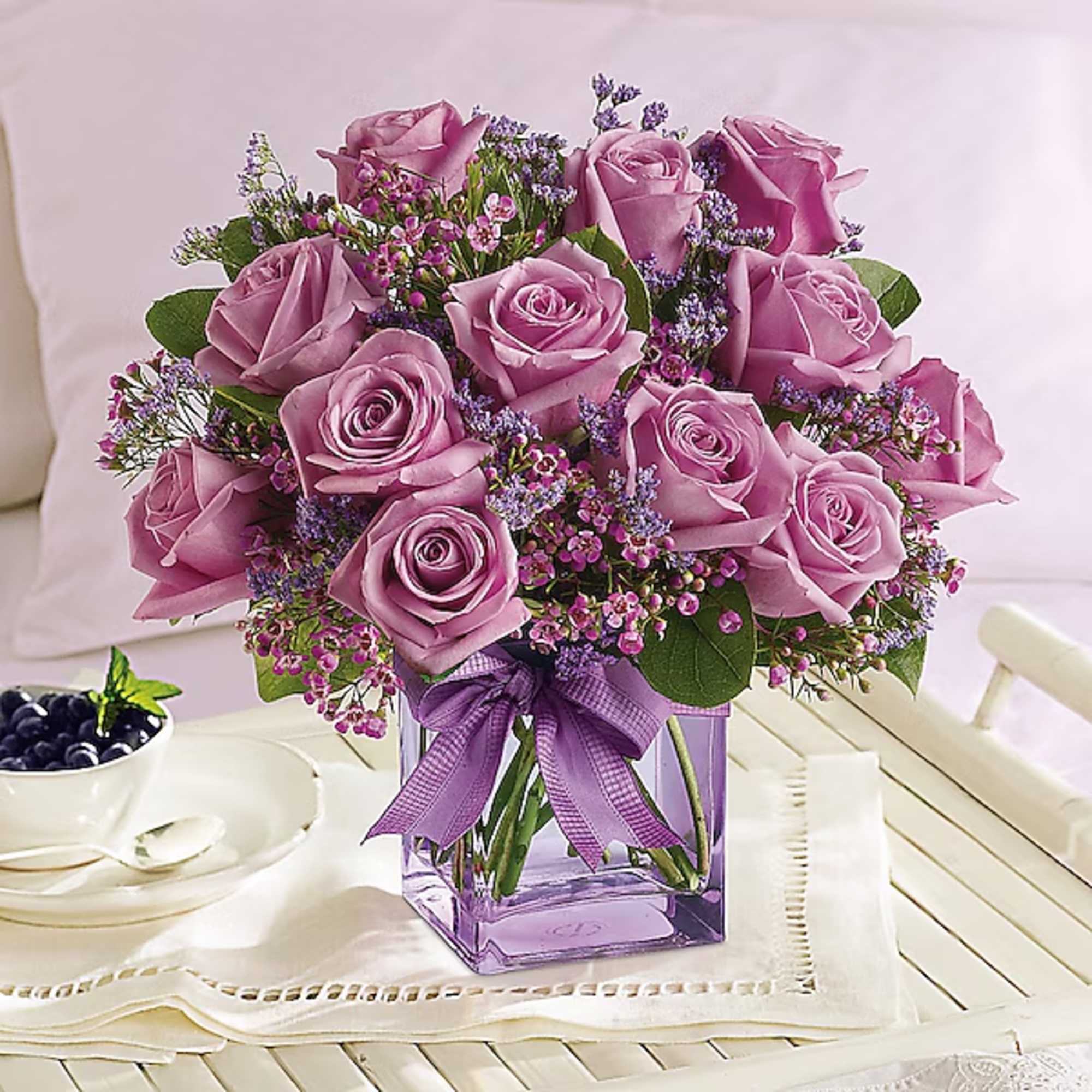 Lavender rose bouquet in a square glass vase with a purple ribbon