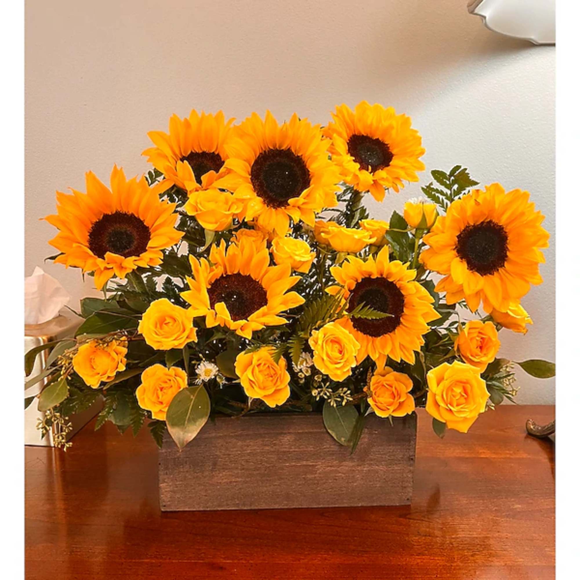 Sunflowers and yellow roses arranged in a rectangular wooden box