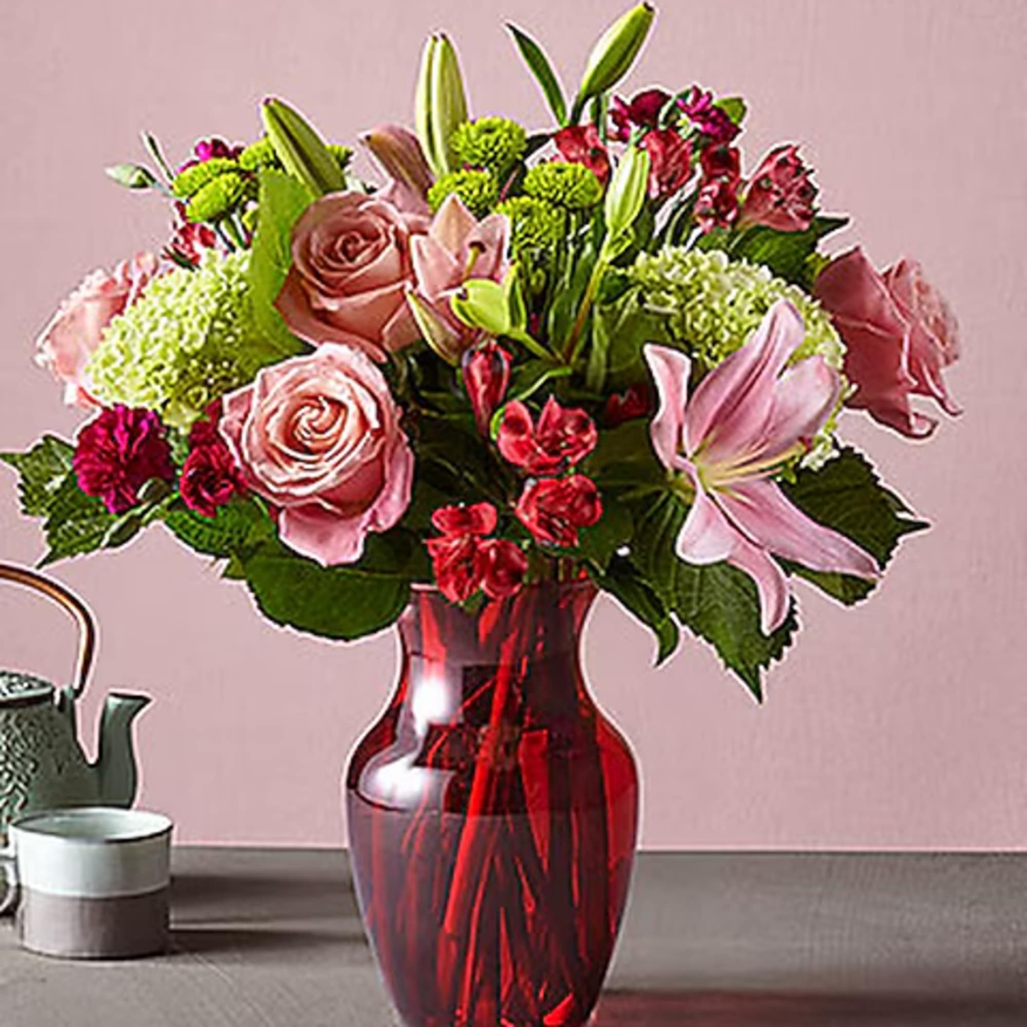 Pink roses and lilies arranged in a red glass vase