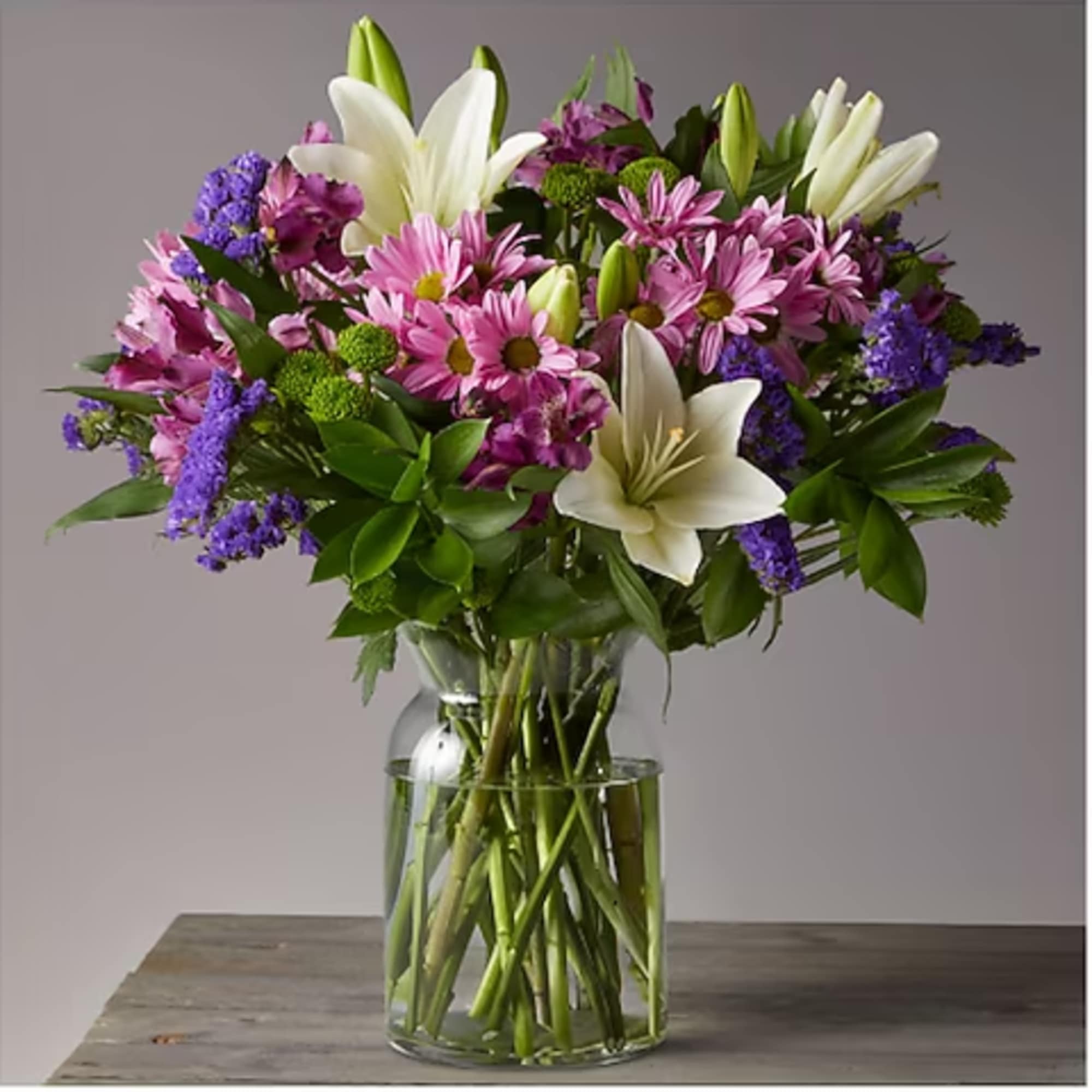 Bouquet of pink daisies and white lilies in a clear glass vase