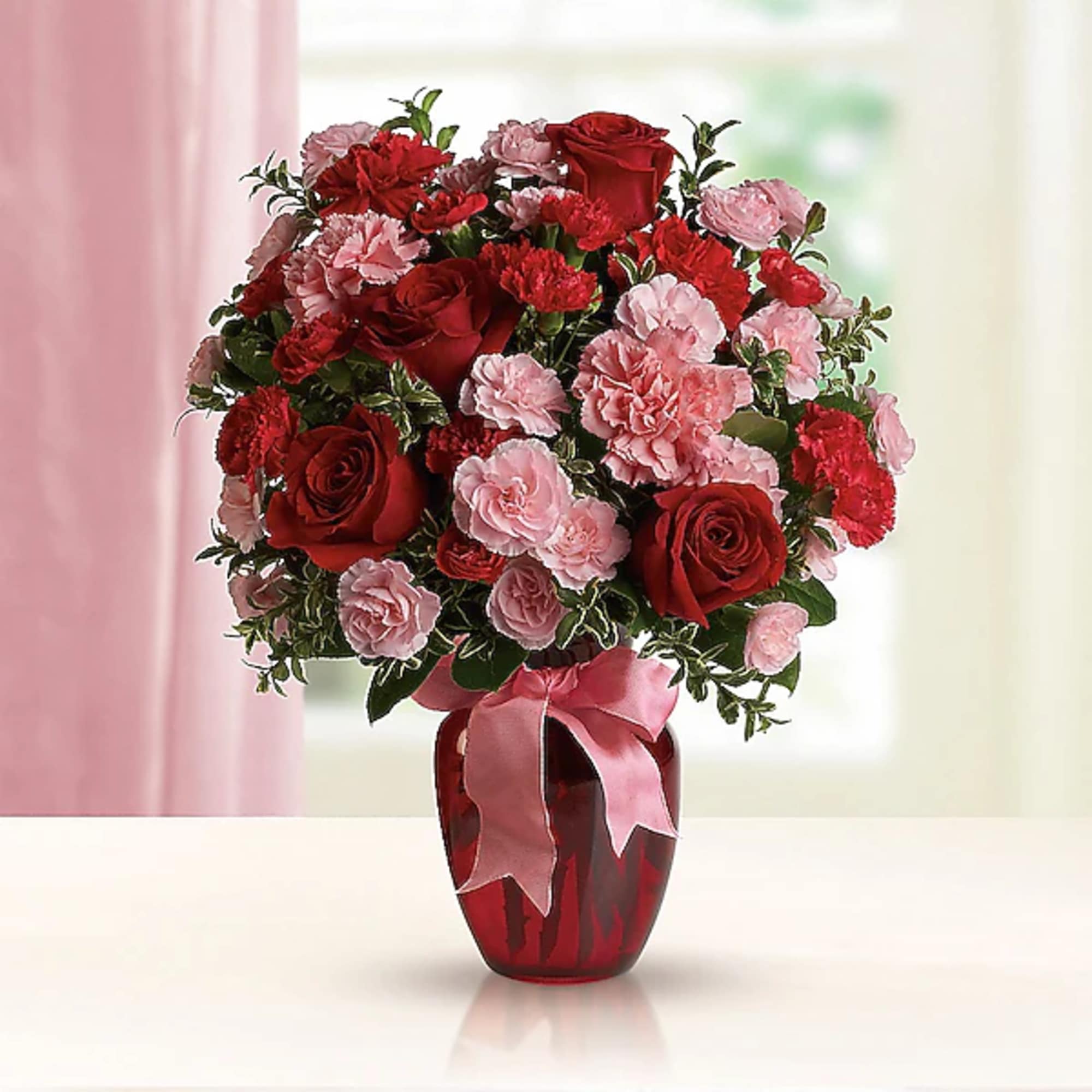 Red roses and pink carnations in a red vase with a pink ribbon, photo 2 of 2