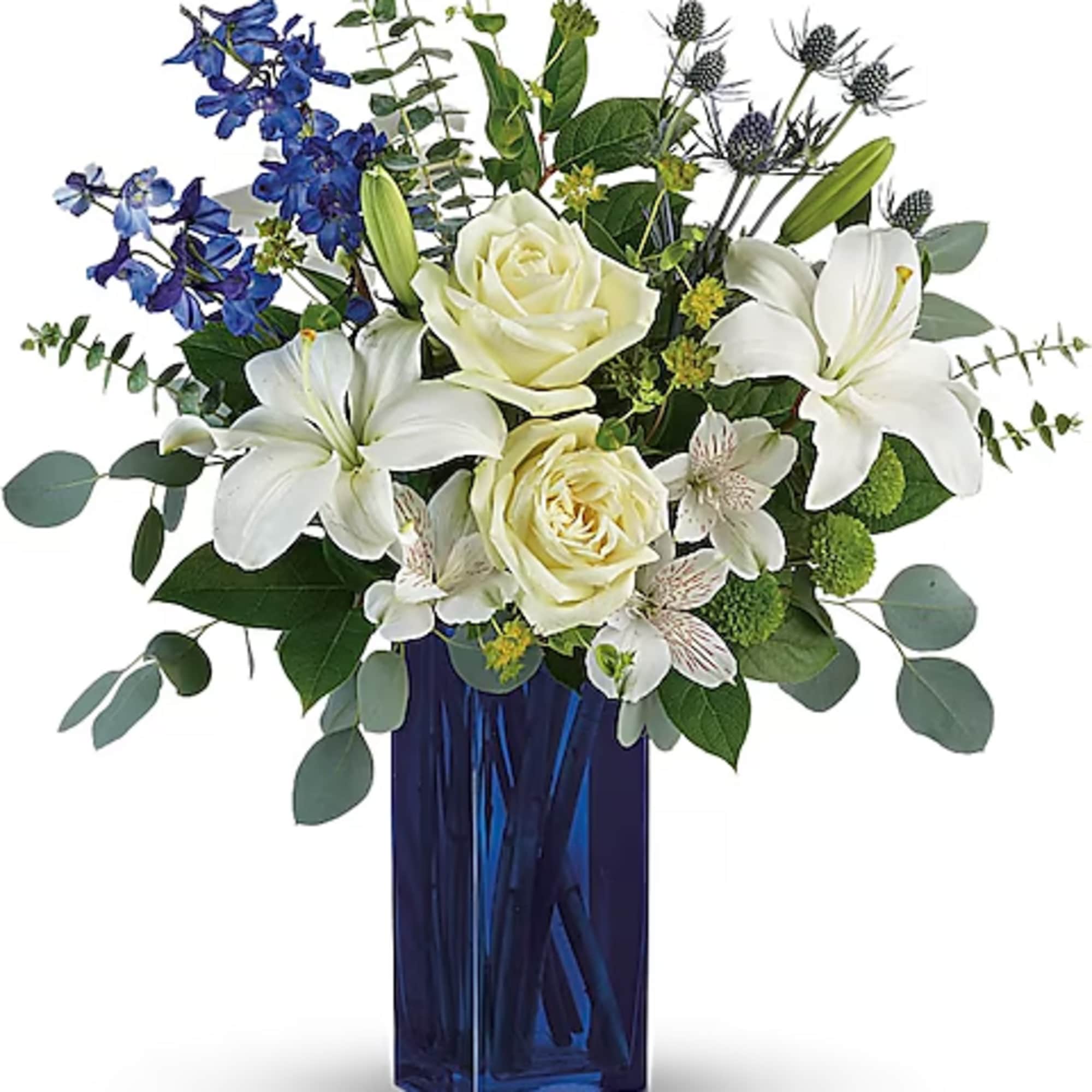 White roses and lilies in a blue glass vase with blue flowers