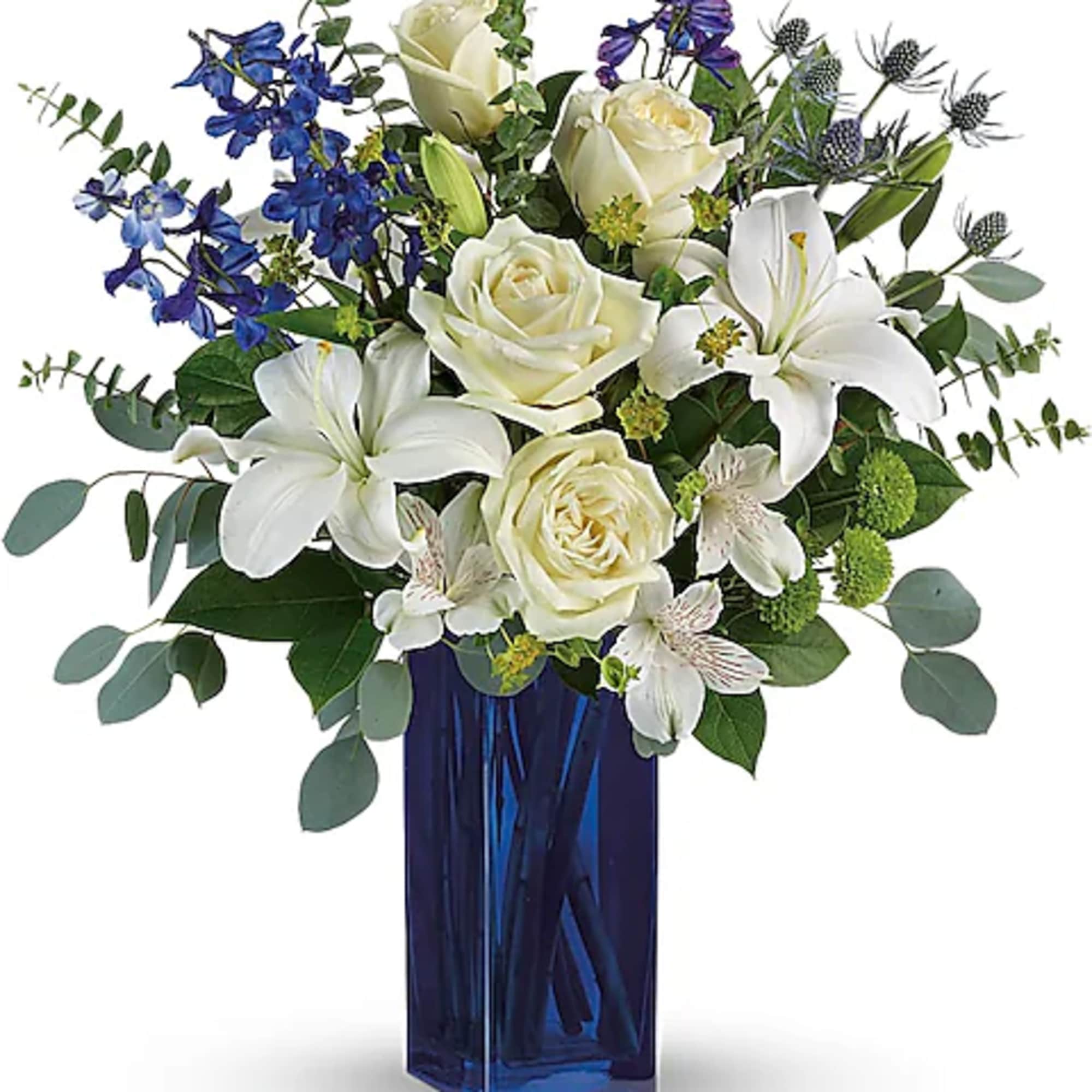 White roses and lilies in a blue glass vase with blue flowers