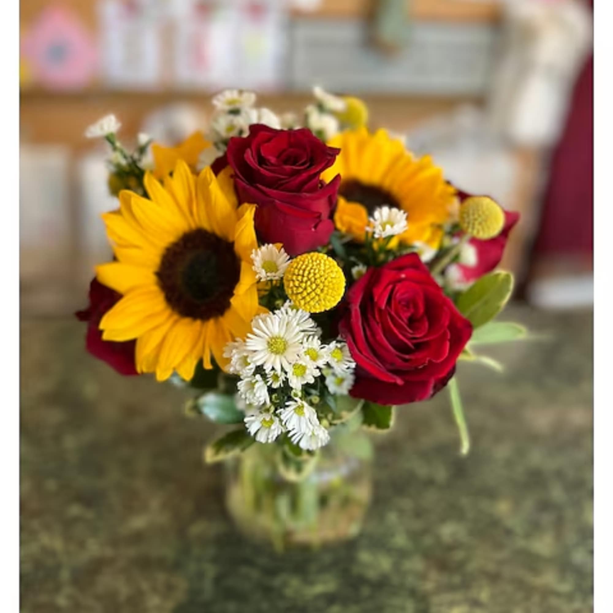 Bouquet of red roses and sunflowers in a glass vase