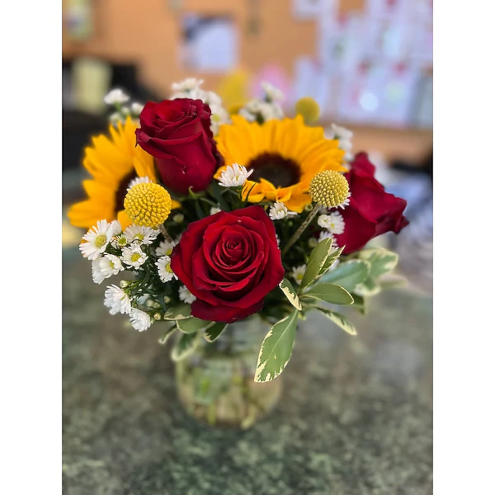Bouquet of red roses and yellow sunflowers in a glass vase