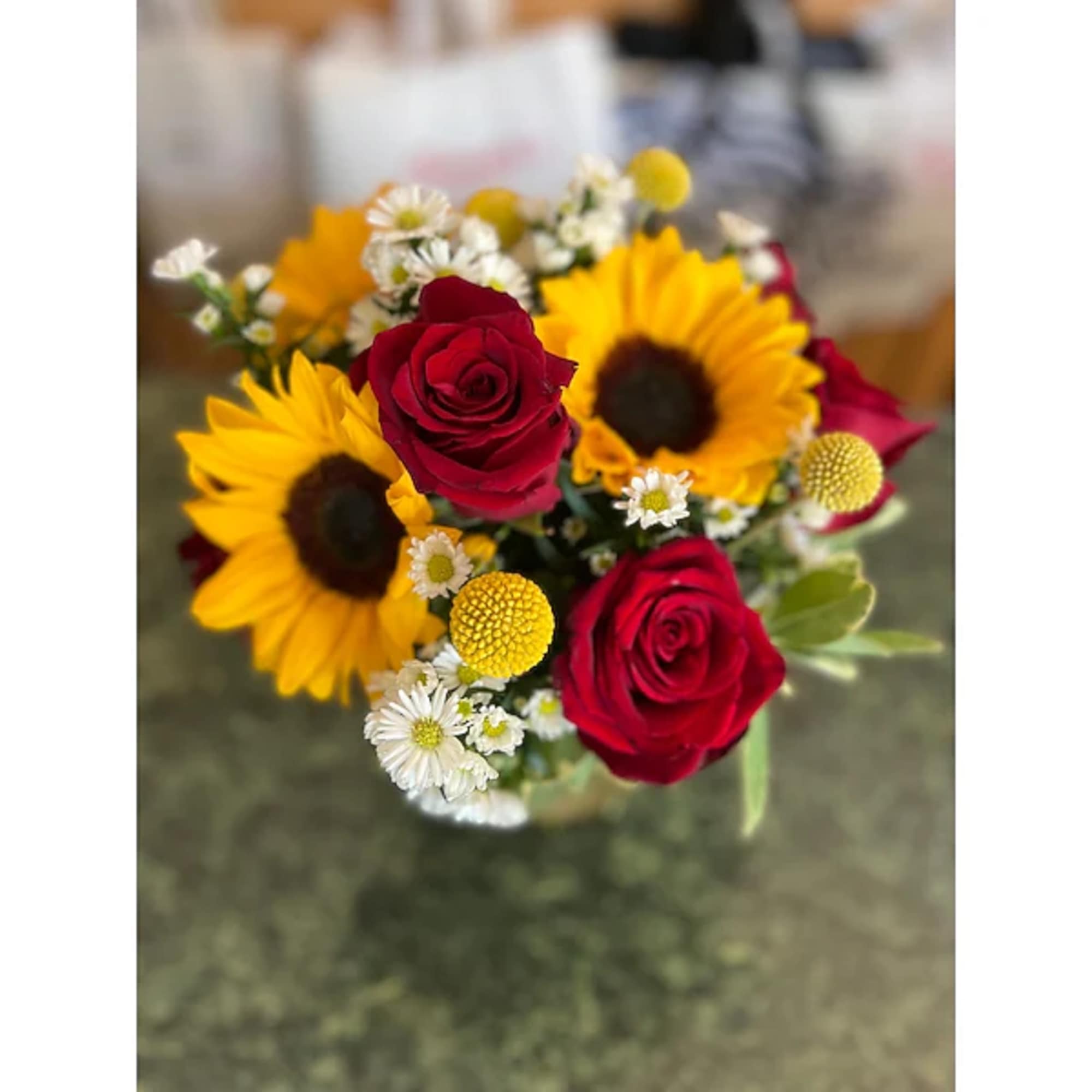 Bouquet of red roses and yellow sunflowers with small white daisies