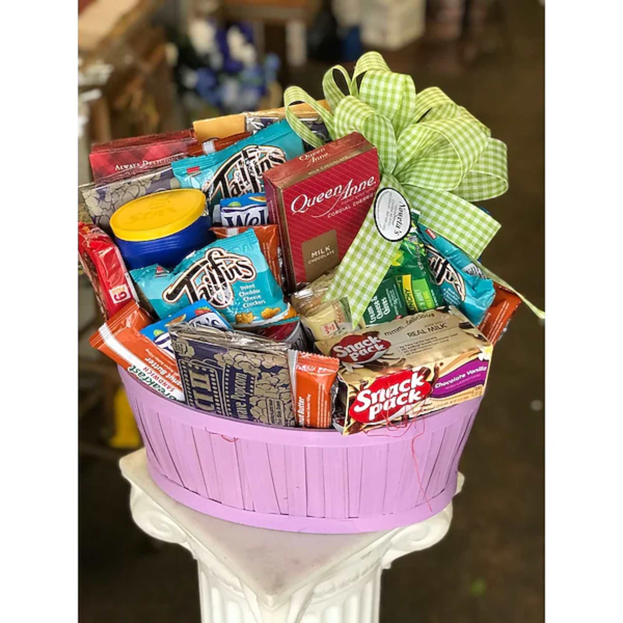 Basket of assorted snack packs tied with a green checkered bow