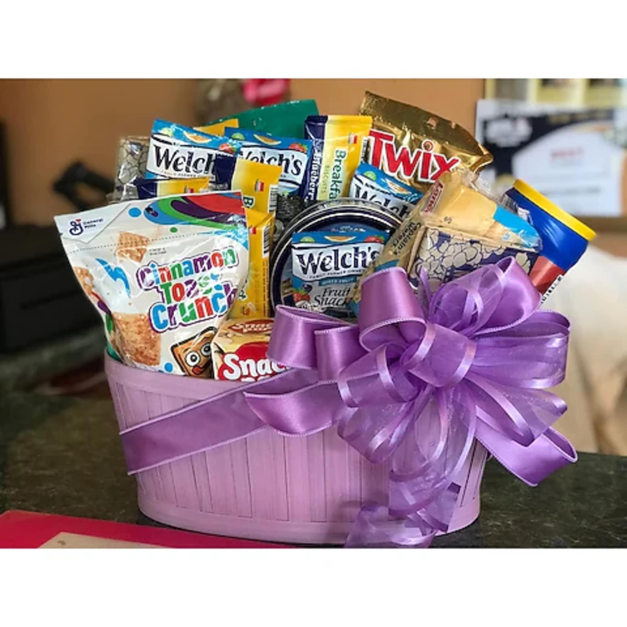 Gift basket filled with assorted snack packs and a purple ribbon bow