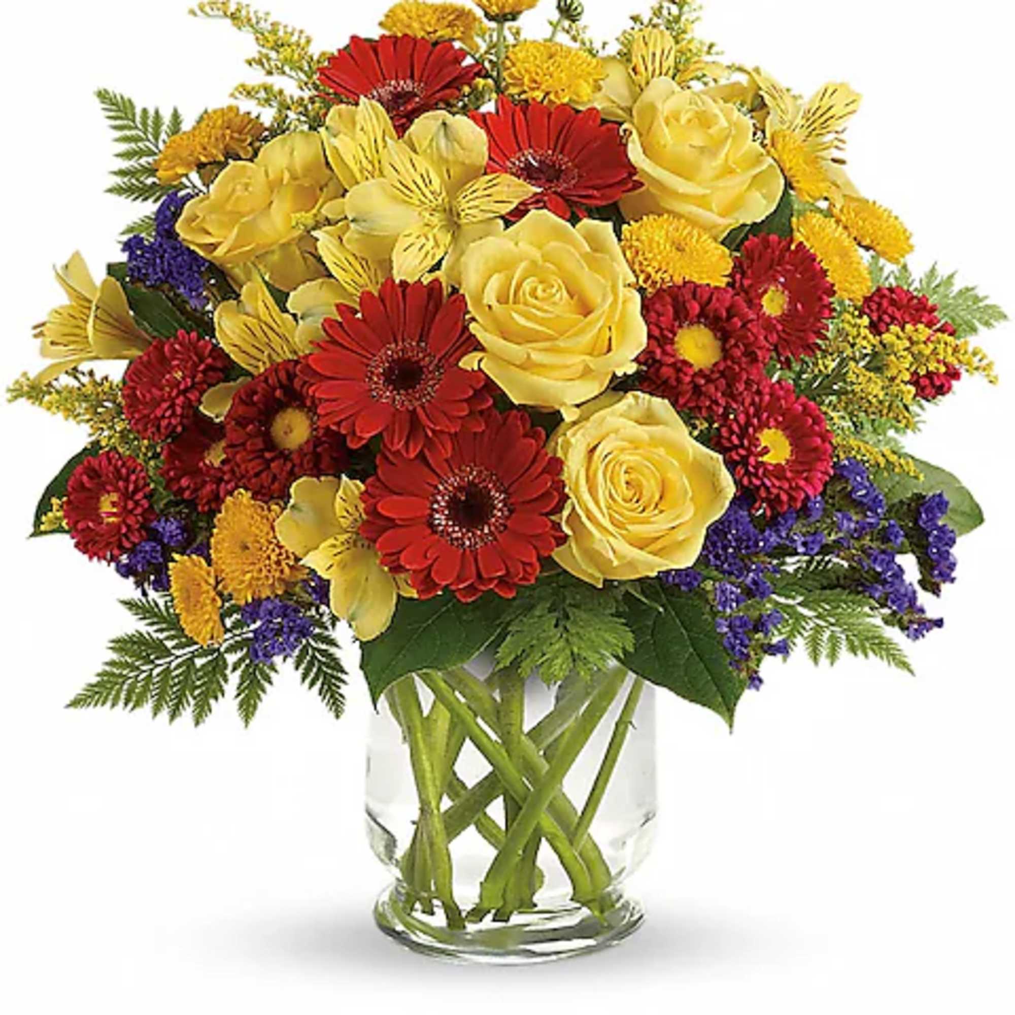 Mixed bouquet of yellow roses, red gerbera daisies, and purple accents in a glass vase