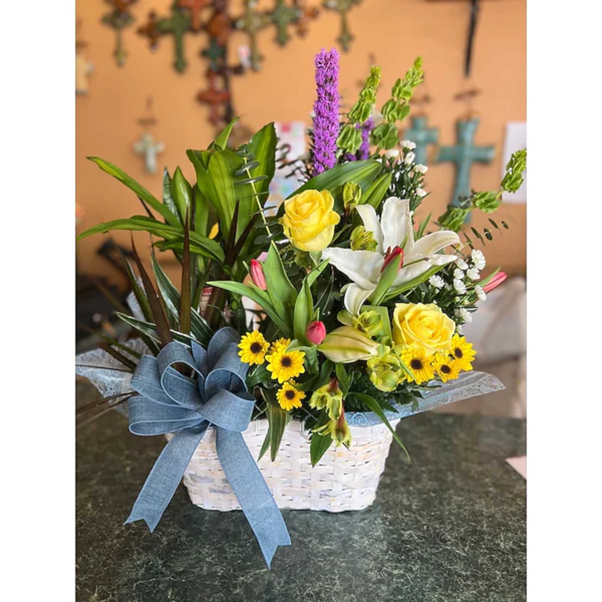 Basket arrangement with yellow roses, white lilies, and a blue ribbon