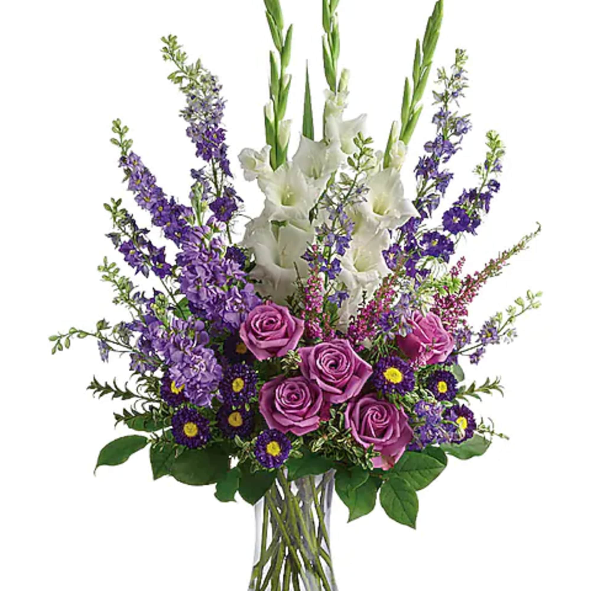 Purple roses and white gladiolus in a clear glass vase