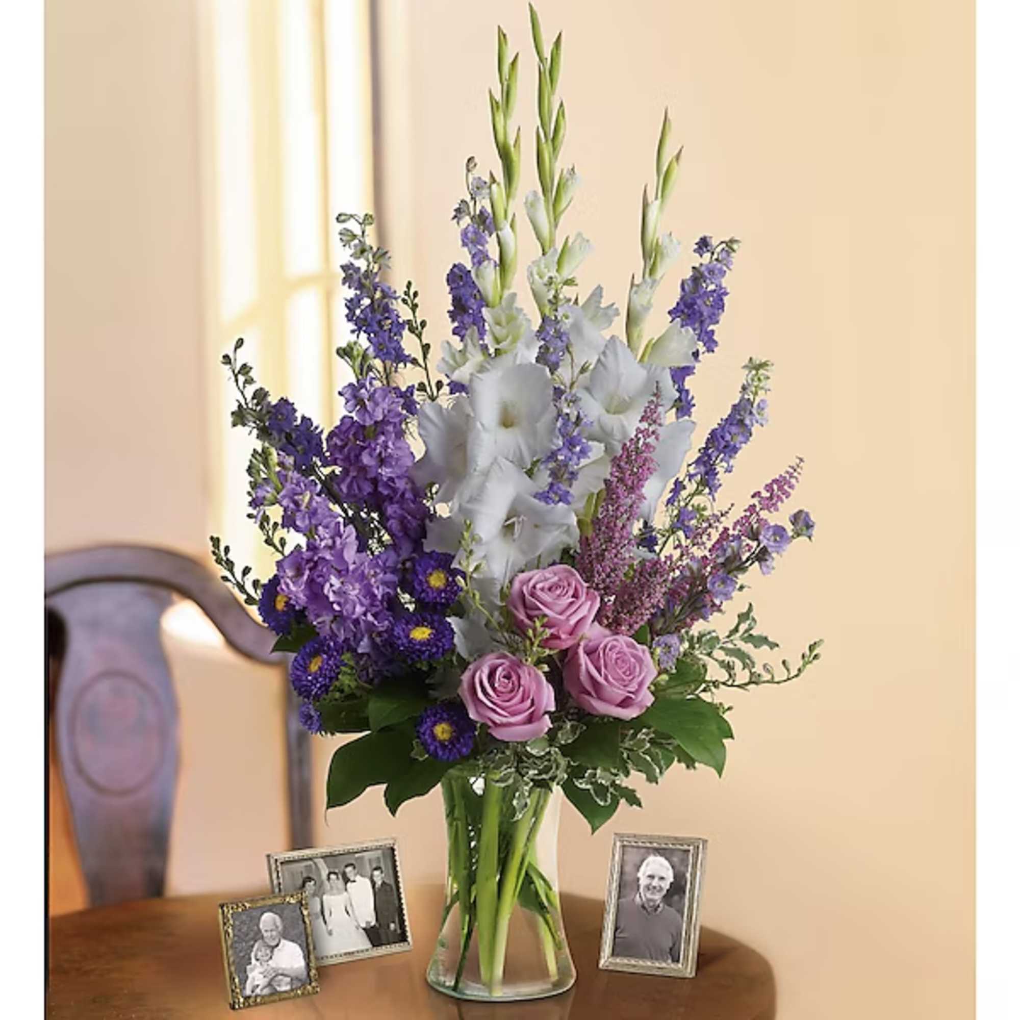 Purple and white floral arrangement in a clear glass vase on a table