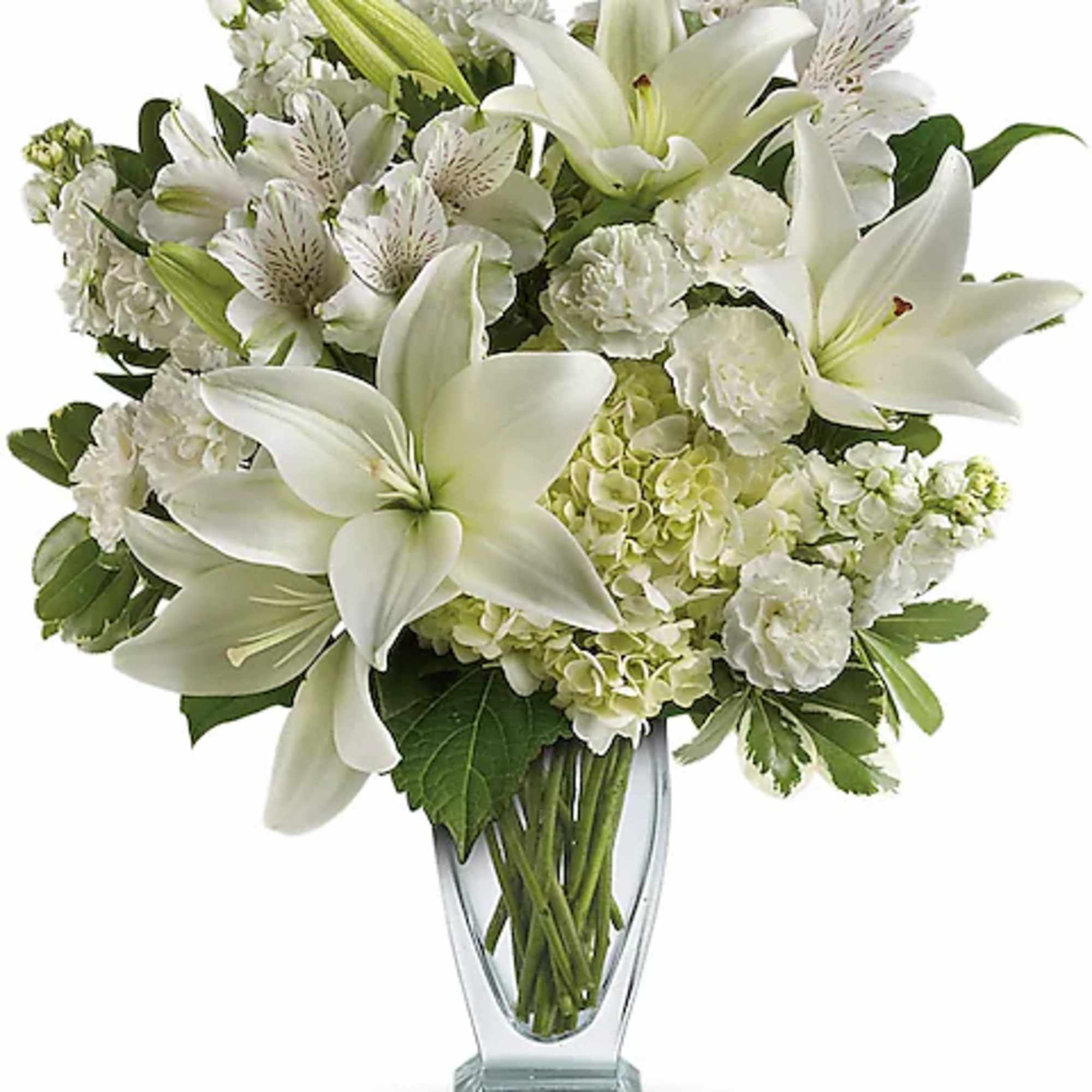 White lilies and mixed white flowers arranged in a clear glass vase