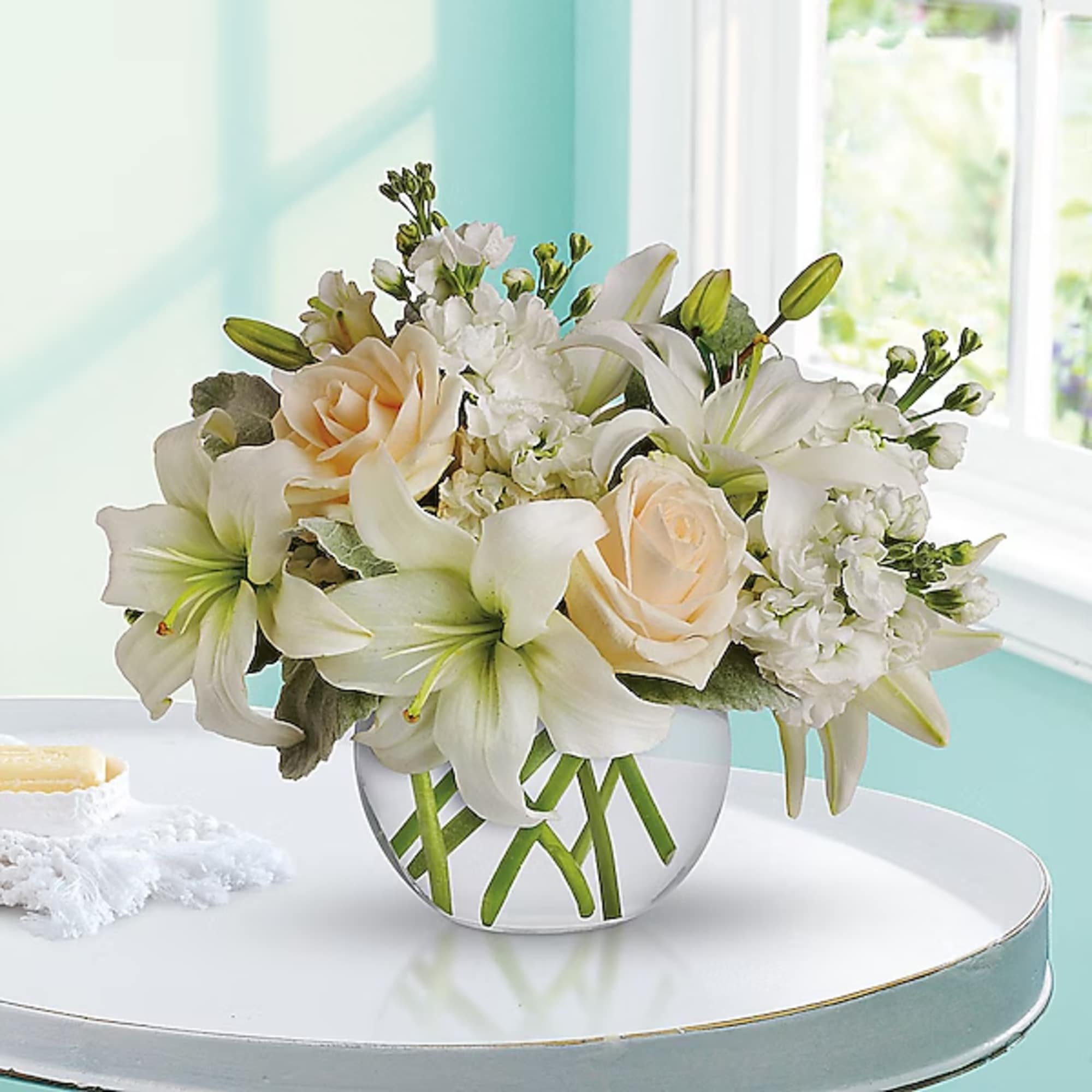 White lilies and pale roses arranged in a clear glass vase