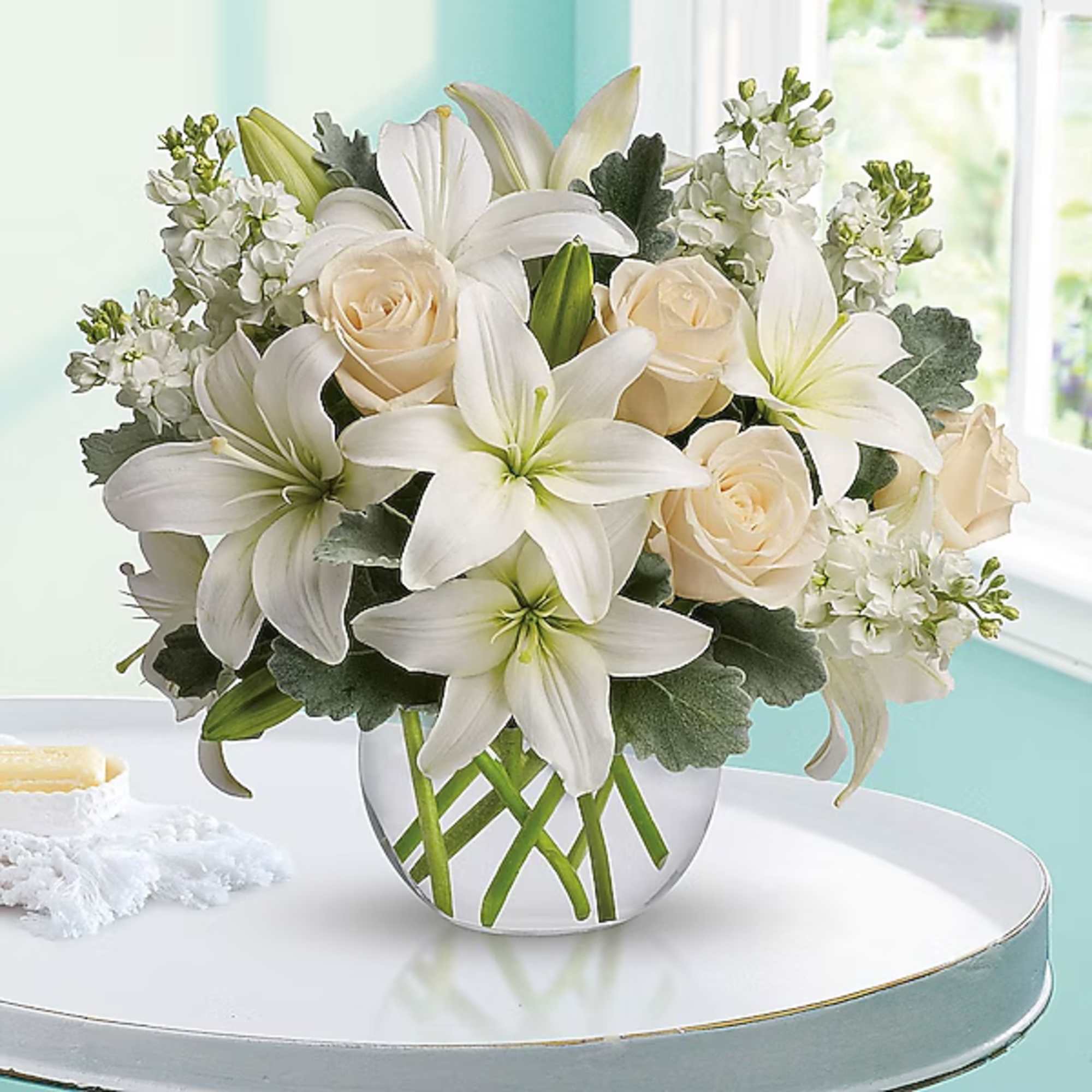 White lilies and cream roses arranged in a clear glass vase, photo 2 of 2