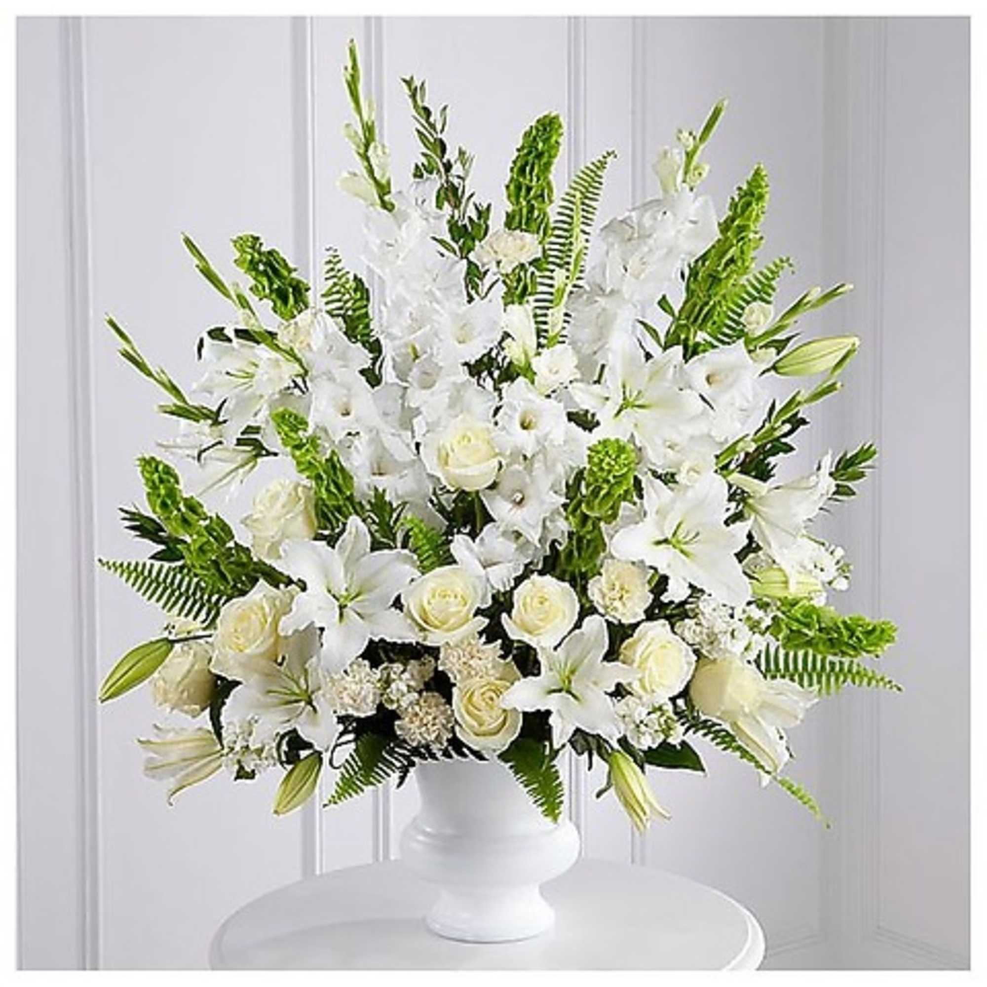 White floral arrangement in a white vase with lilies and roses