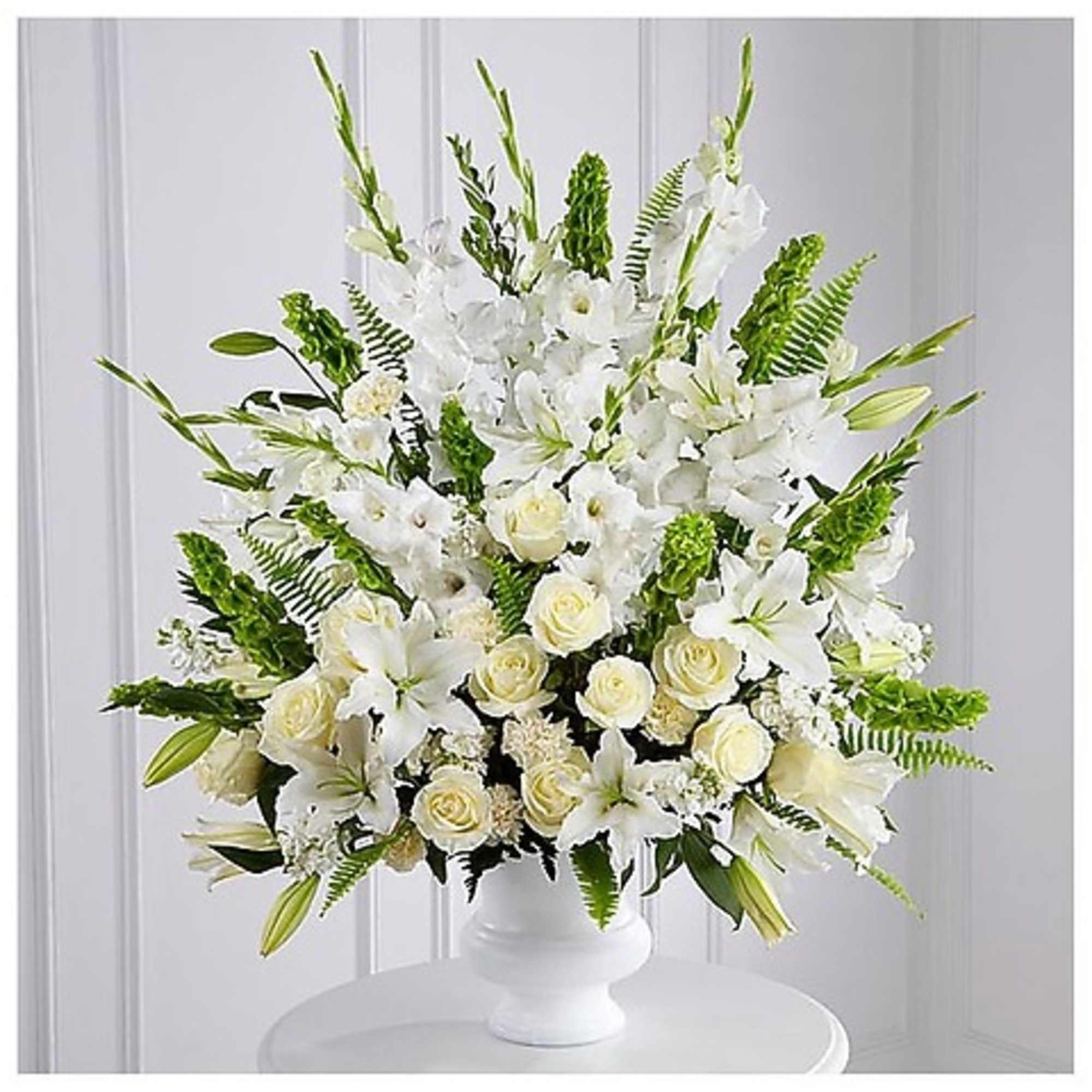 White lilies and roses arranged in a white vase