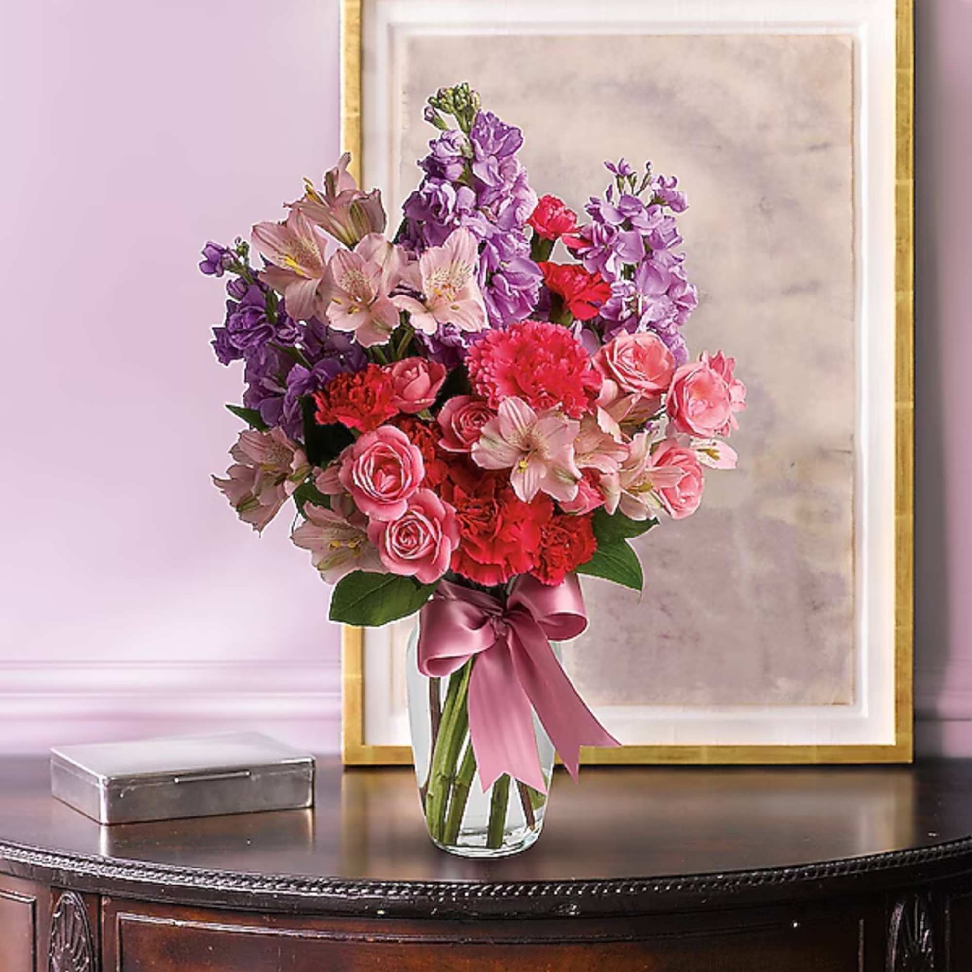 Pink and purple mixed bouquet in a clear glass vase with a ribbon