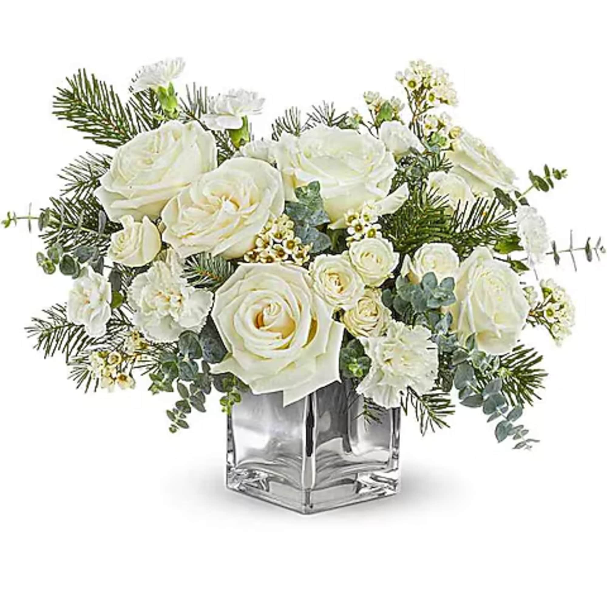White roses arranged in a clear square vase with evergreen accents