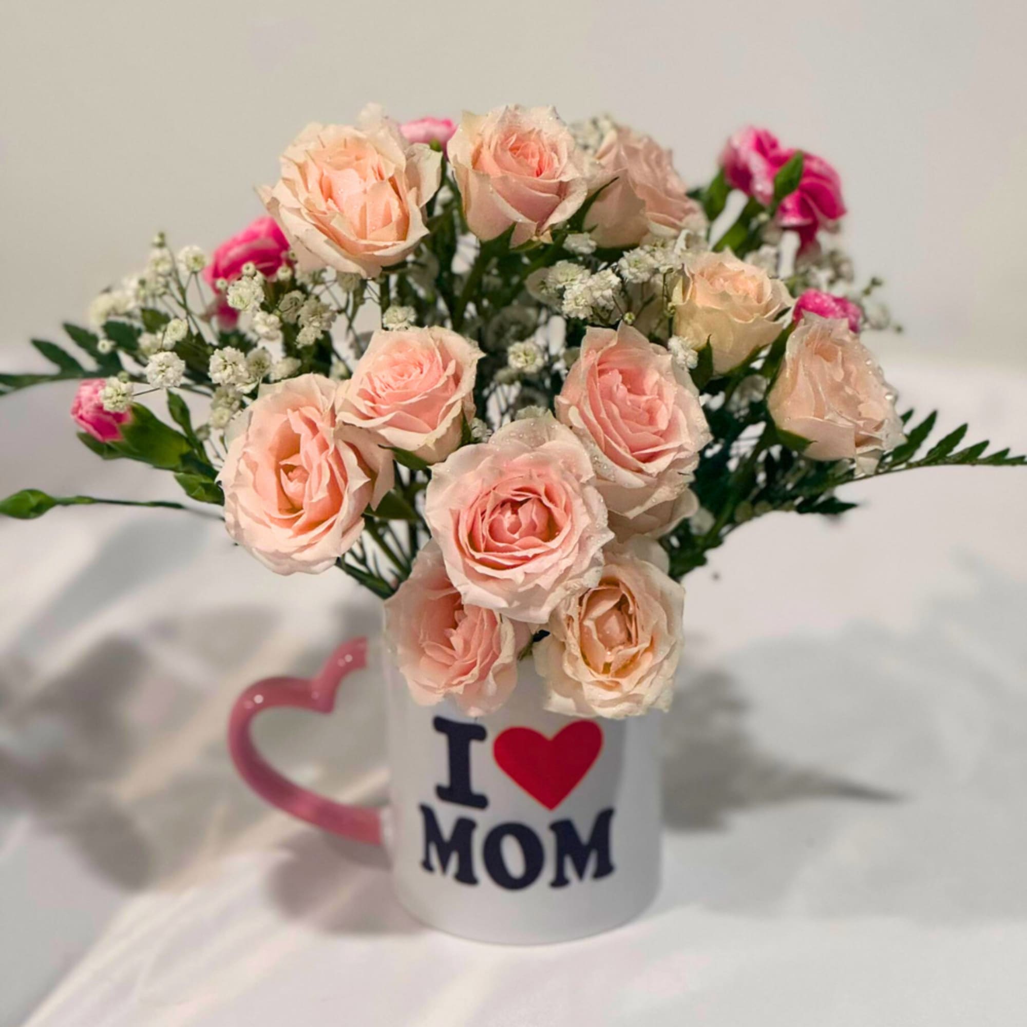 Pink roses arranged in a mug that says I love Mom