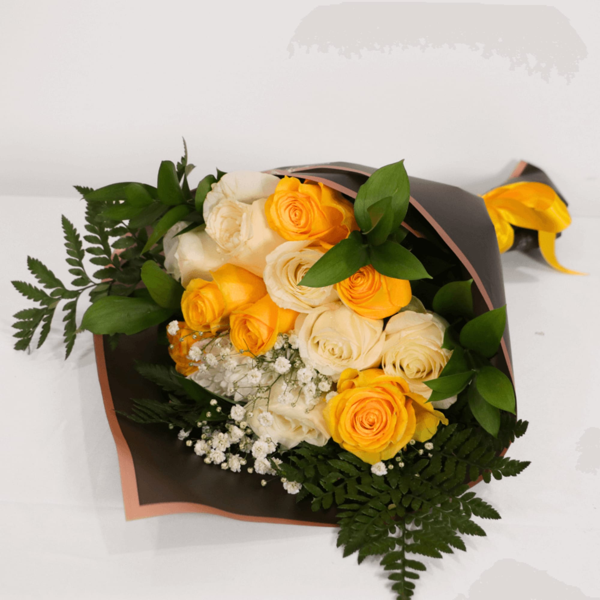 Bouquet of yellow and cream roses wrapped in dark paper