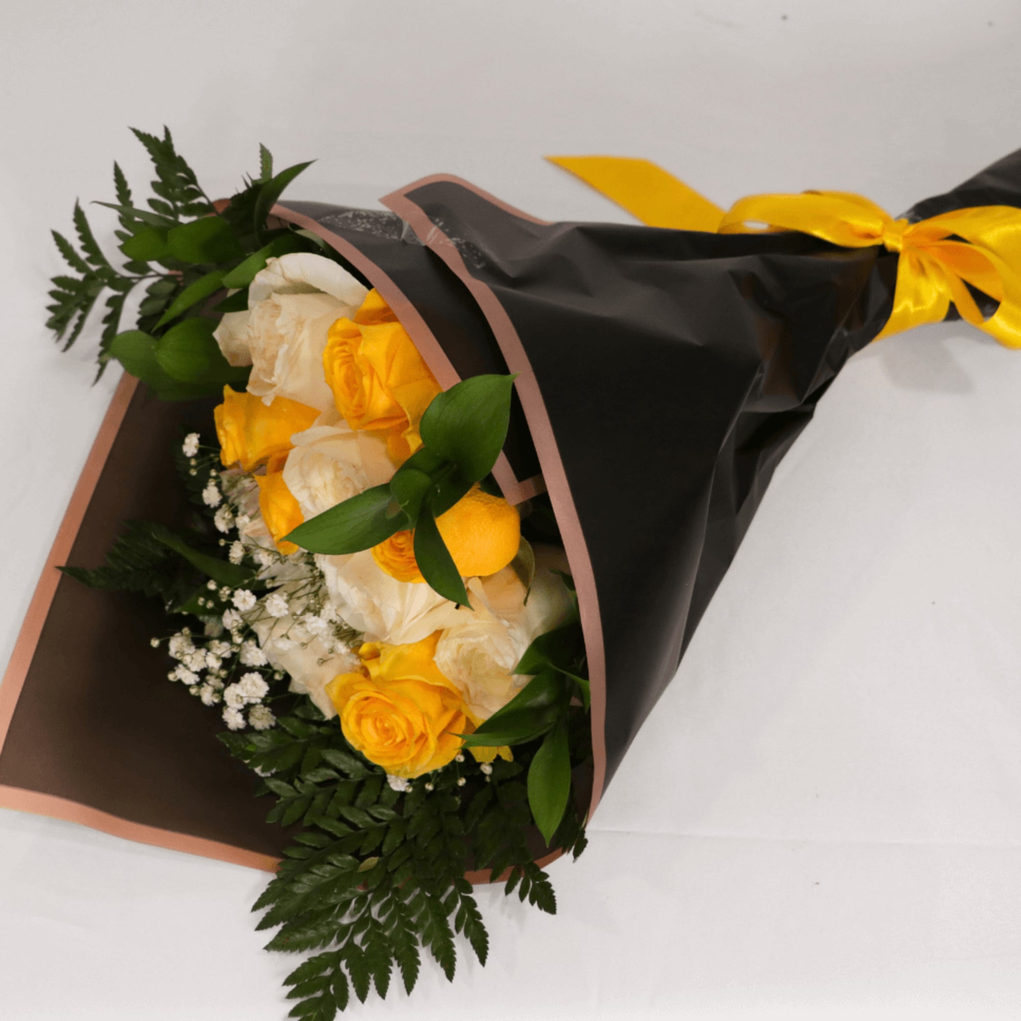 Bouquet of yellow and white roses wrapped in black paper with a yellow ribbon