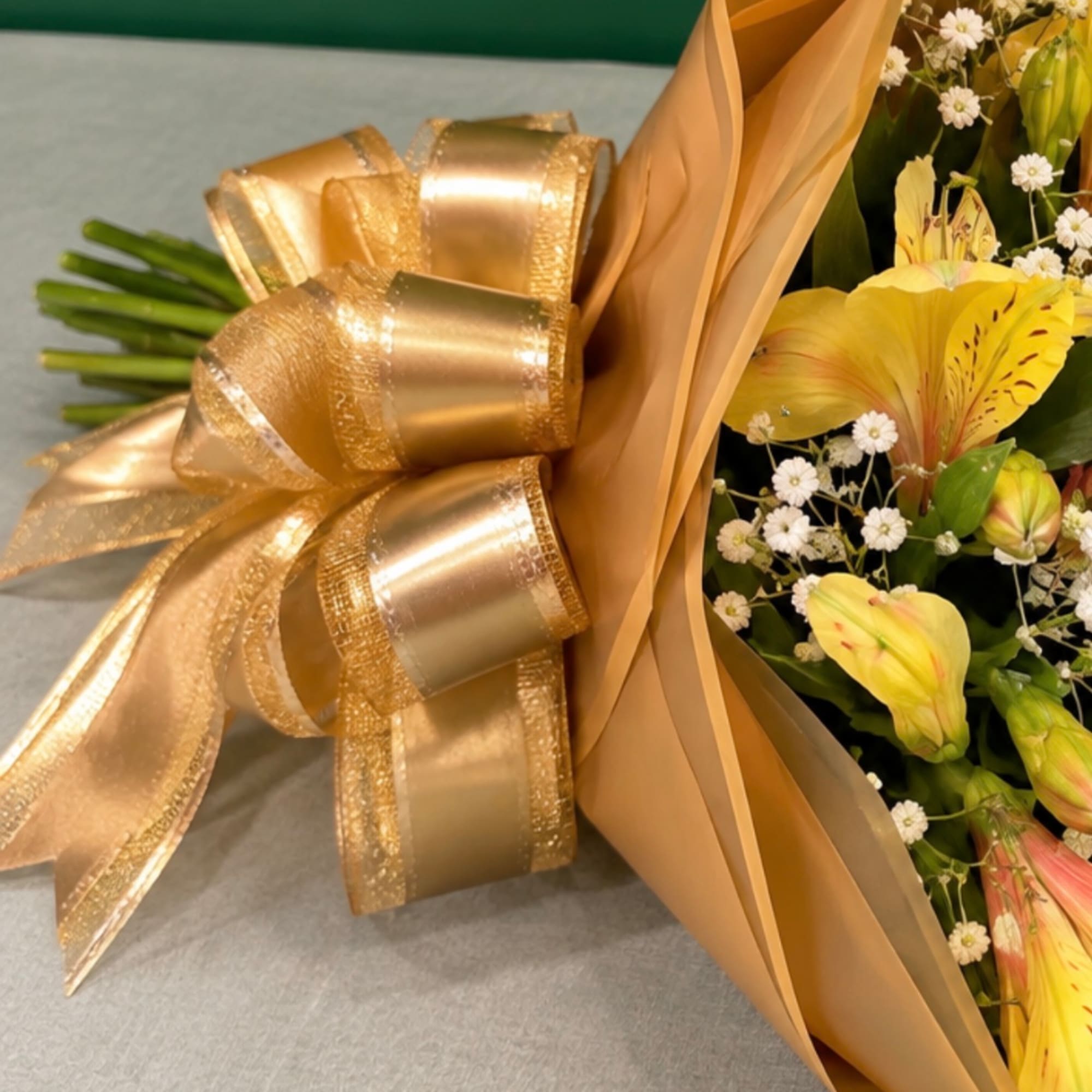 Bouquet with yellow flowers wrapped in gold paper and ribbon