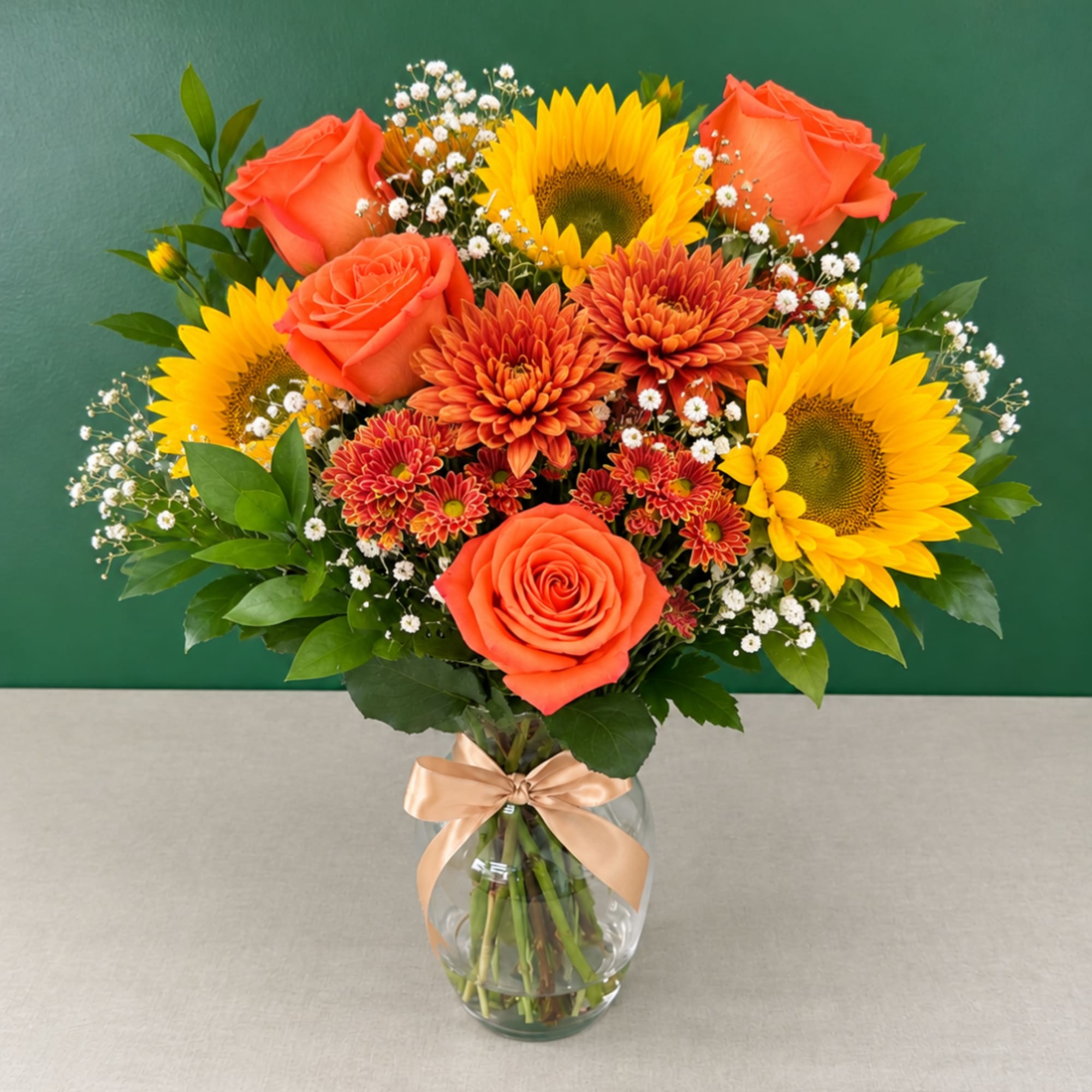 Bouquet of orange roses, sunflowers, and chrysanthemums in a glass vase