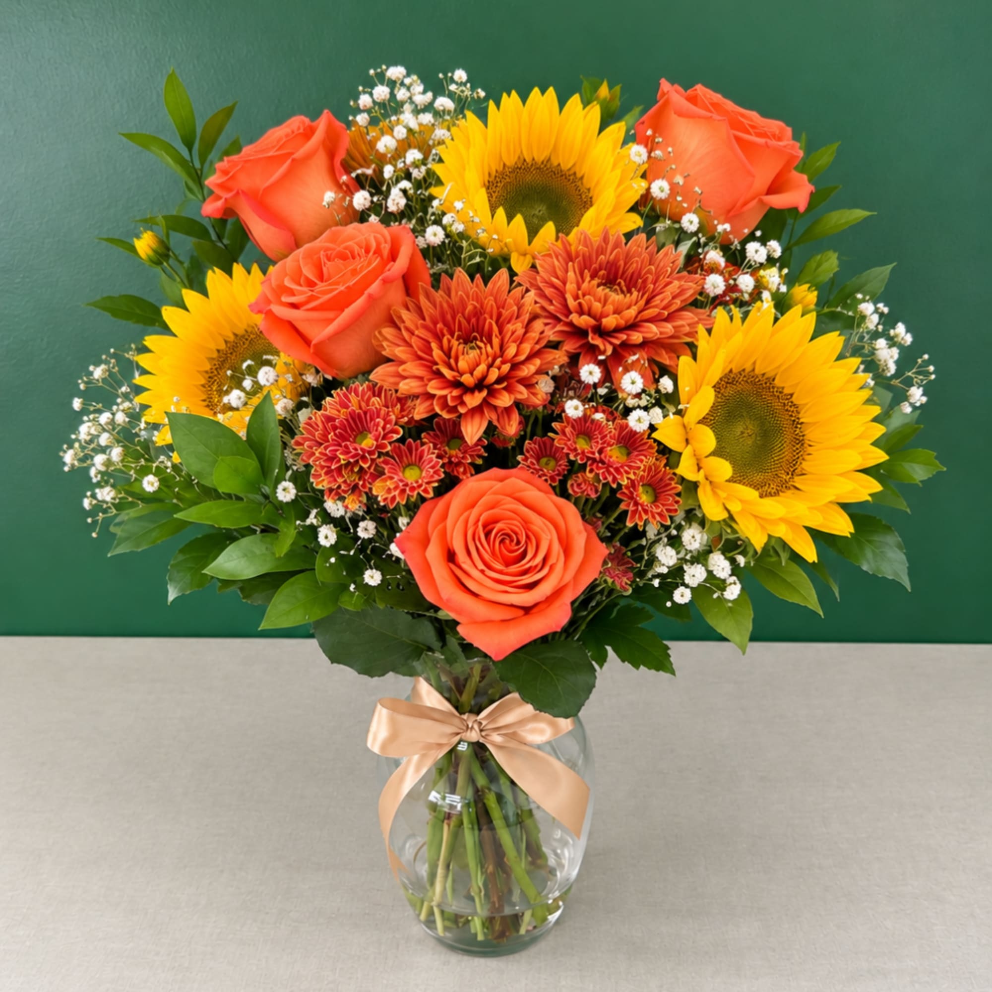 Bouquet of orange roses and sunflowers in a clear glass vase